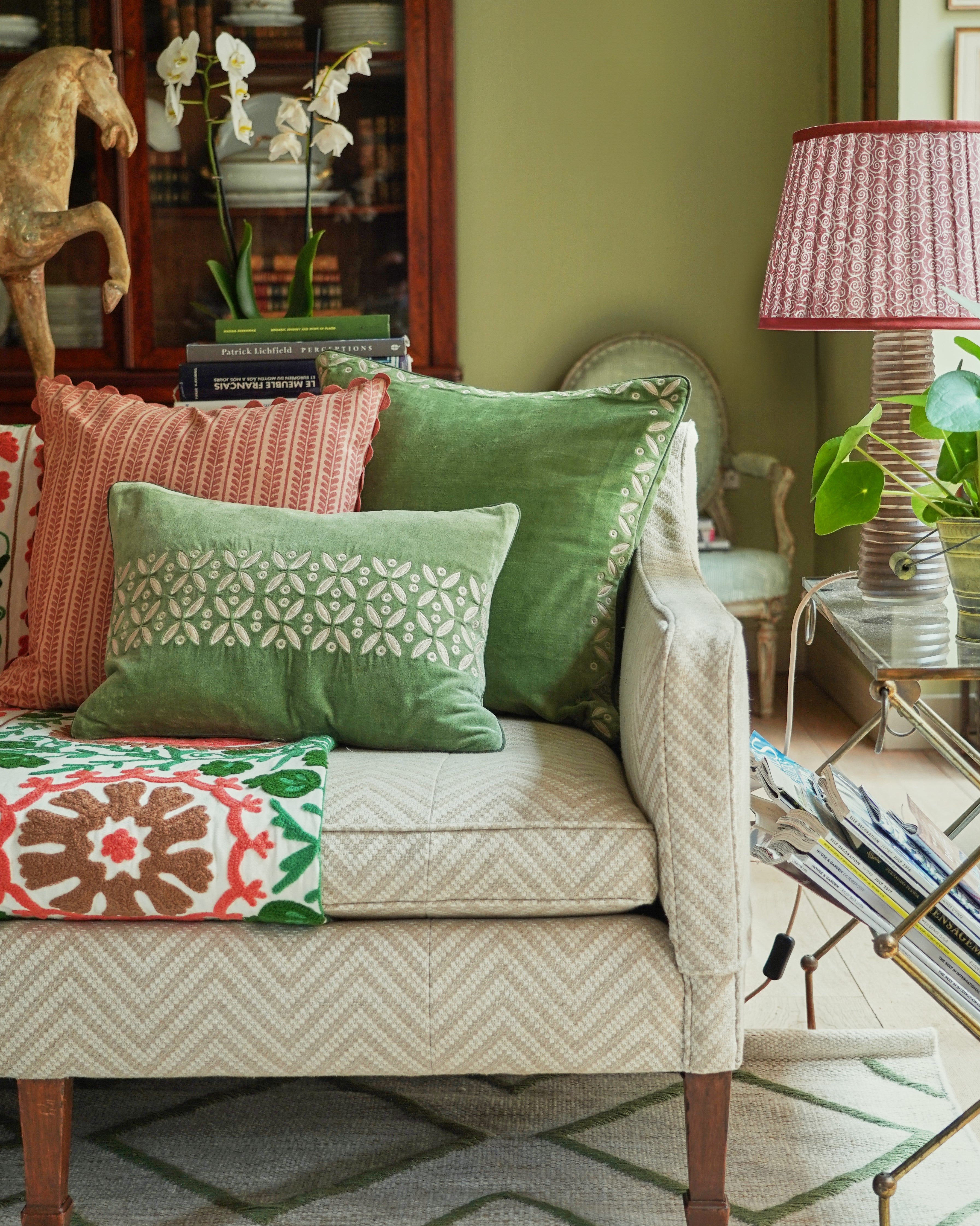 a pink and green selection of cushions on a sofa