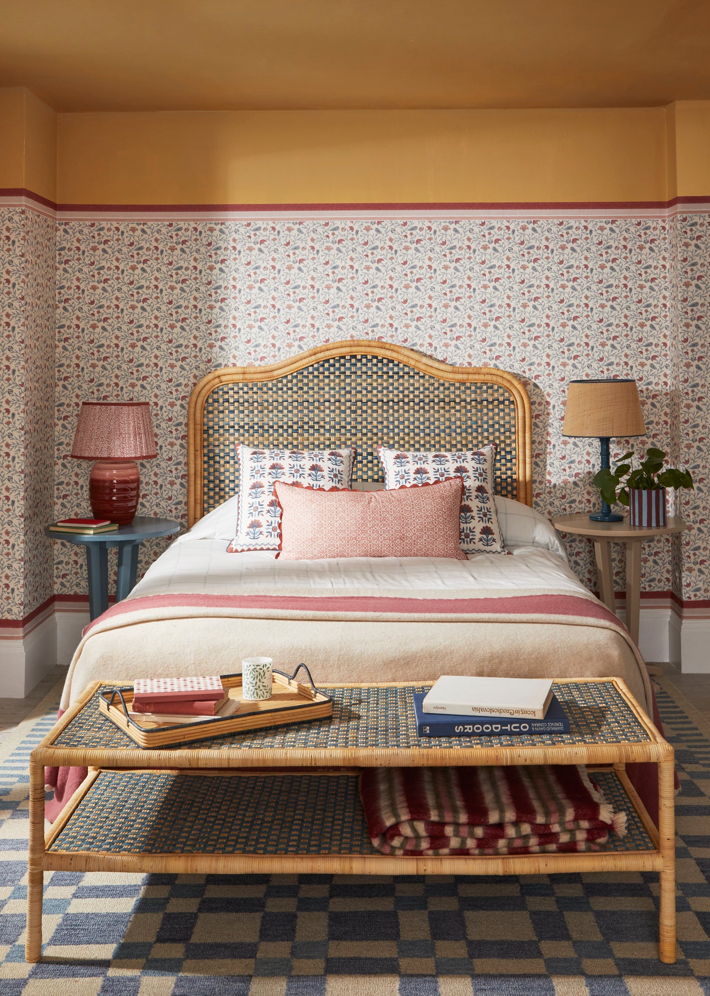Red and blue bedroom lifestyle image featuring, the Andalusia wallpaper, Rattan headboard and ottoman