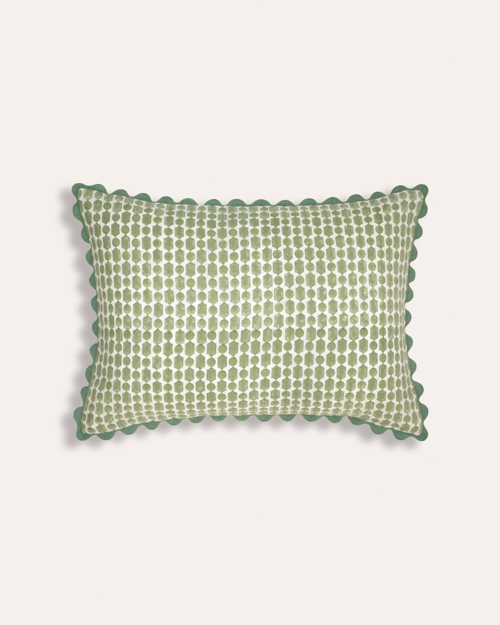 A rectangular cushion with a green geometric block print design and blue ricrac trim.