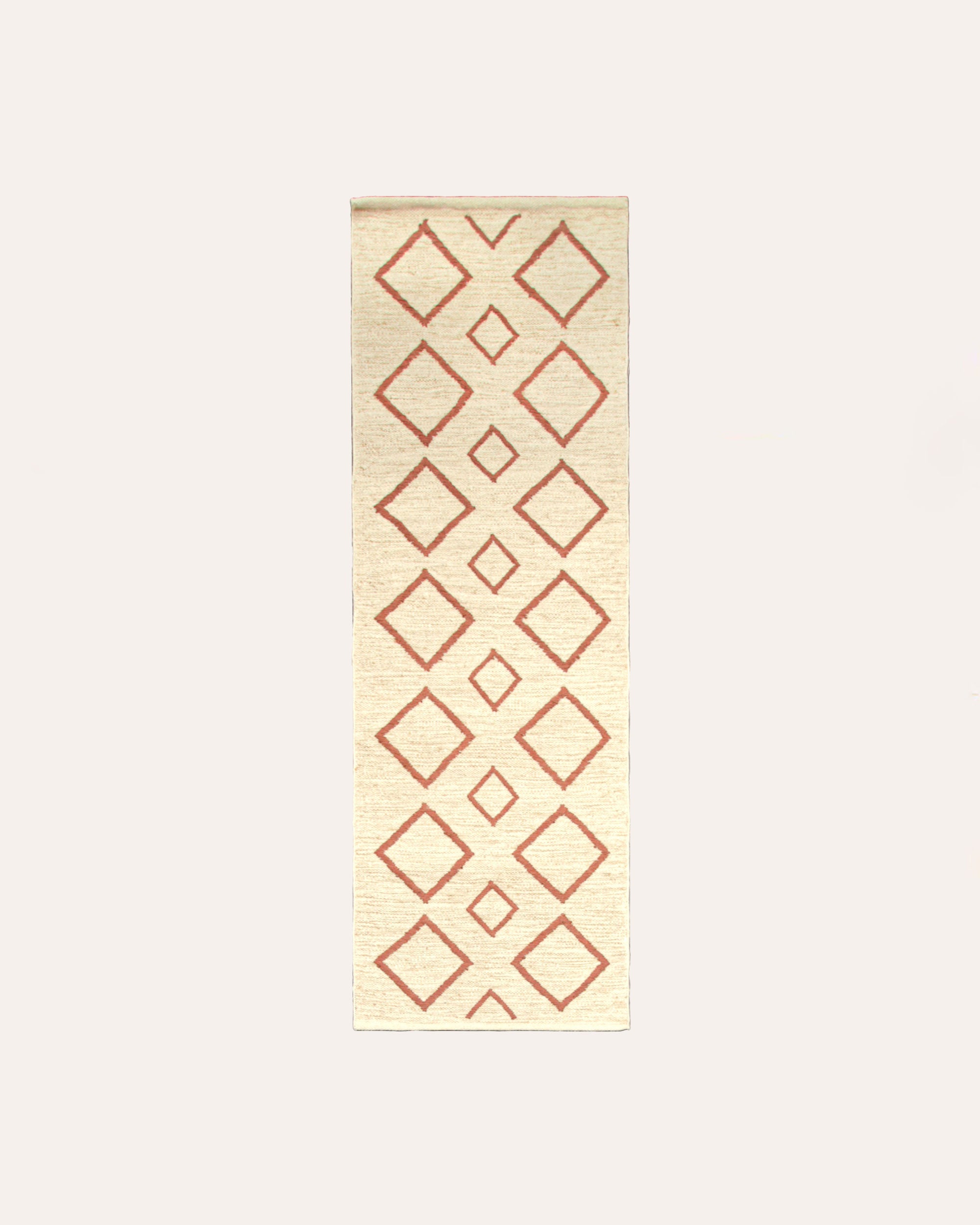 A runner rug with a geometric diamond pattern in pink on an off-white background.