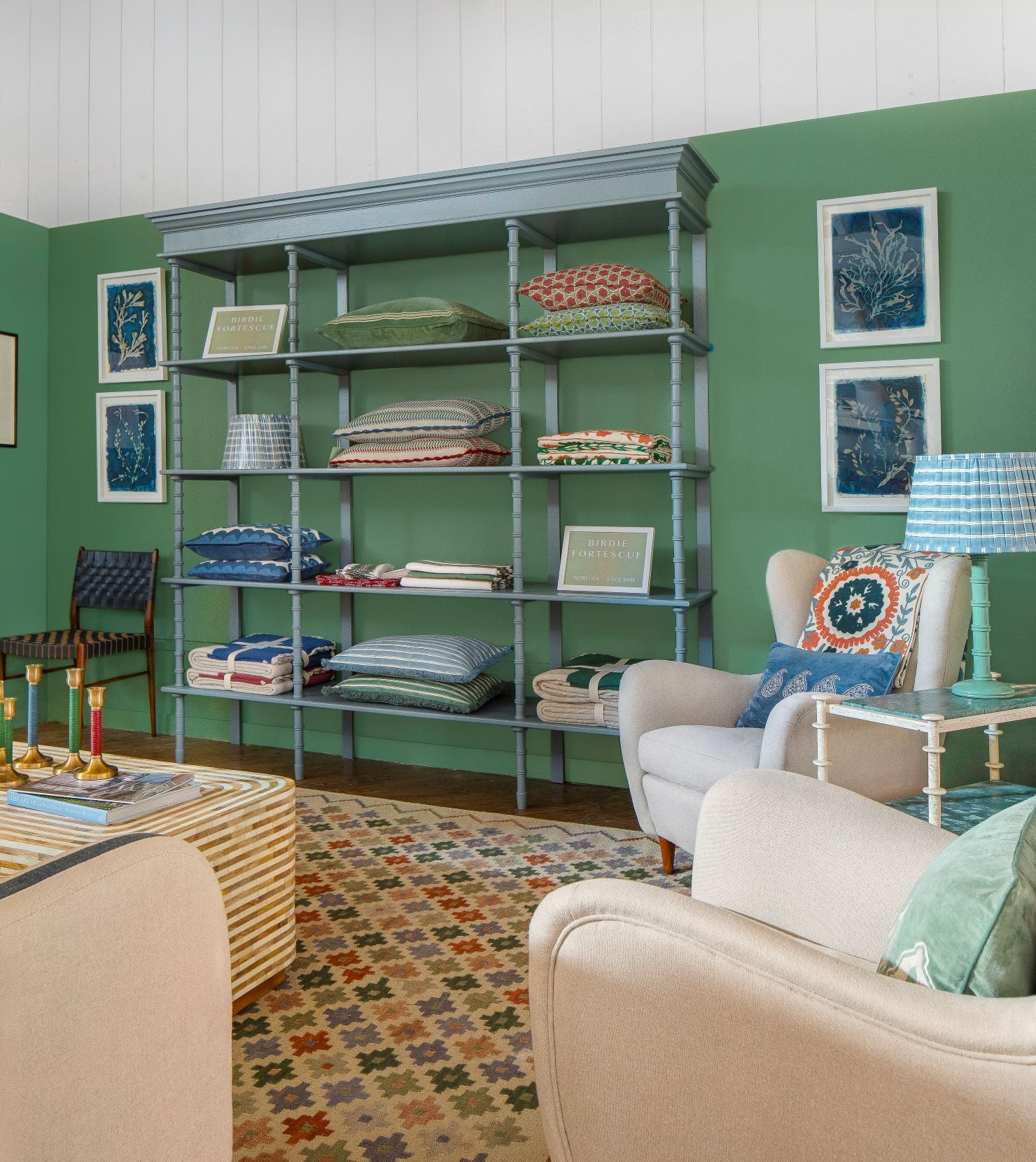 Living room with a bookshelf, armchair, and sofa against a green wall.