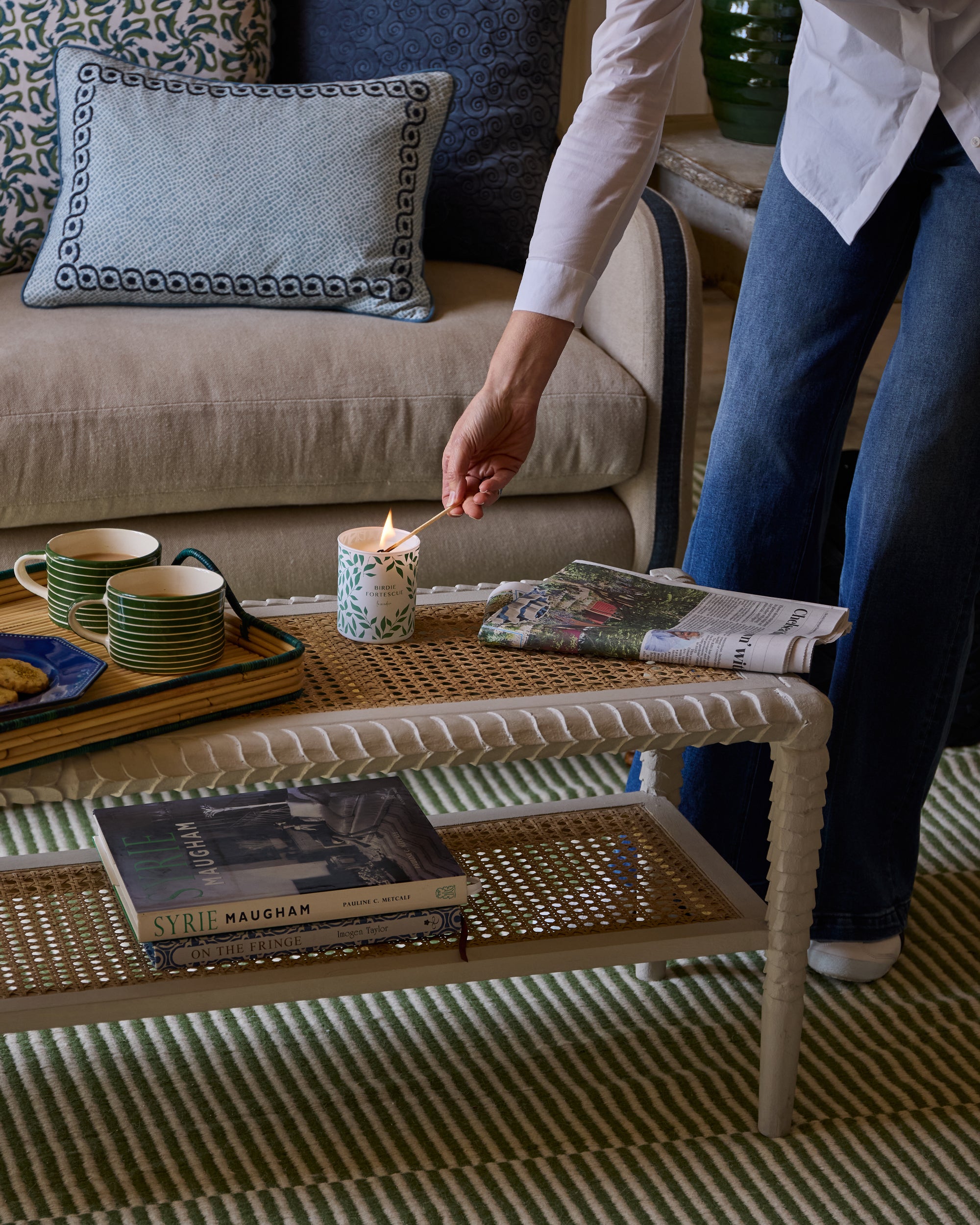 Person lighting the Birdie Fortescue Signature candle on a coffee table in a living room.