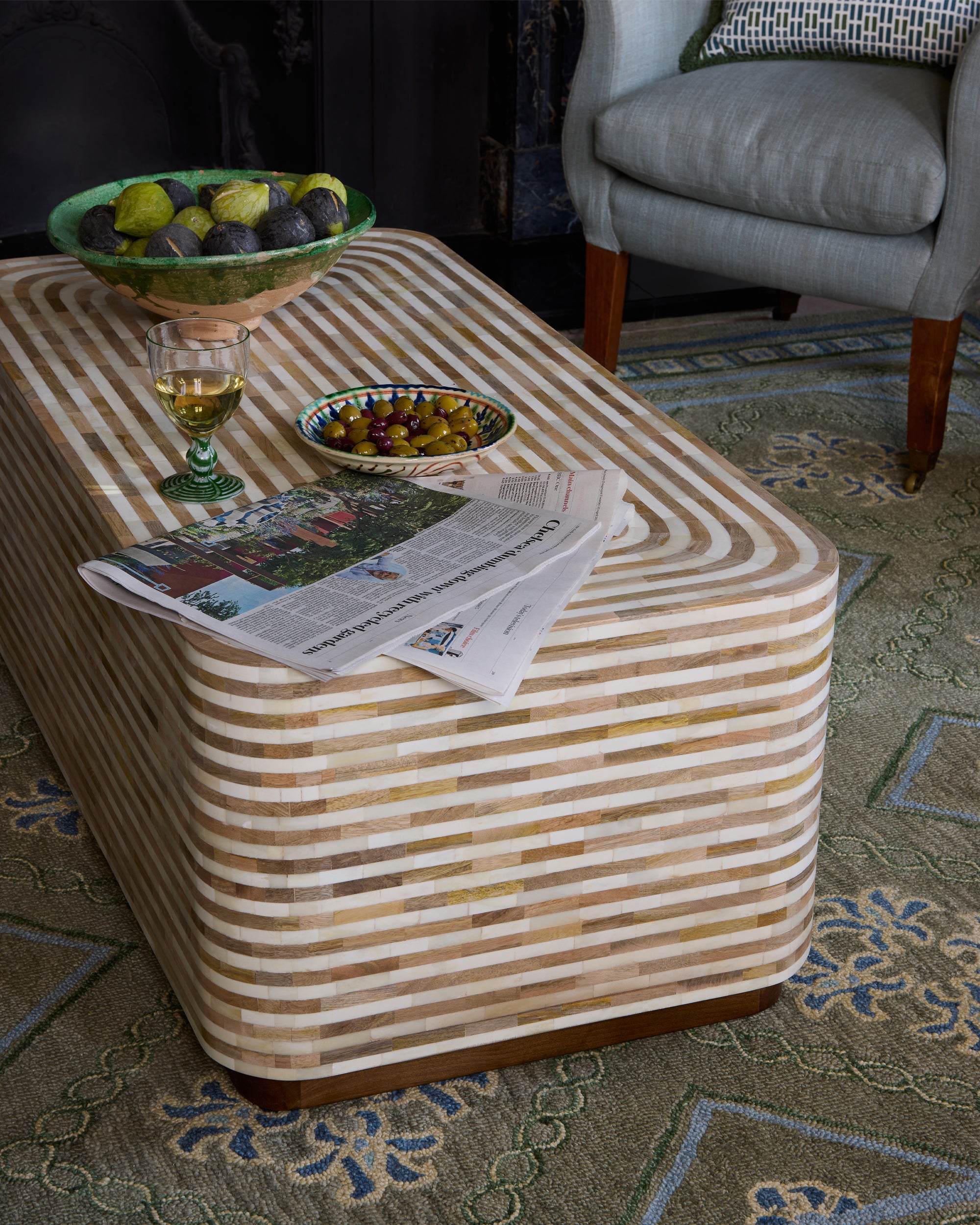 Striped Havana coffee table with a glass, newspaper, and fruit bowl on top in a living room setting.