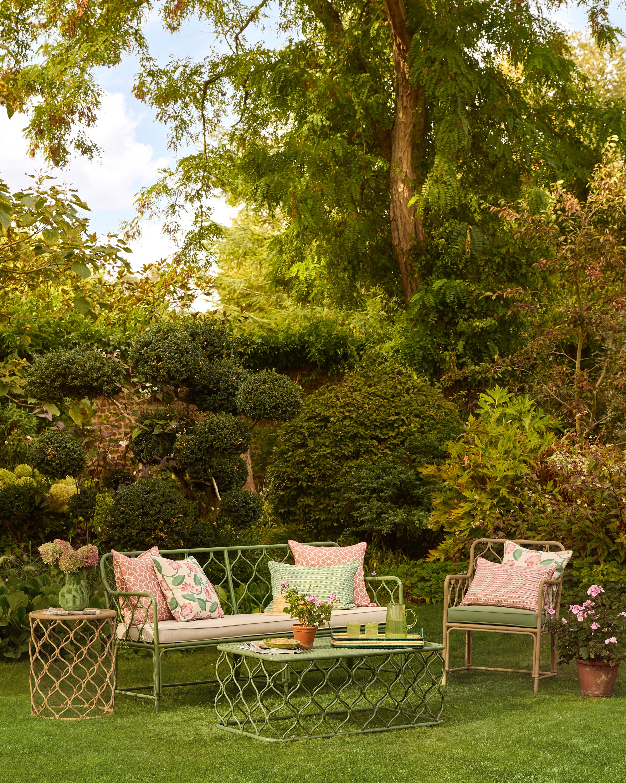 Scenic summer garden with green and natural Curato aluminium furniture, decorated with spring summer accessories