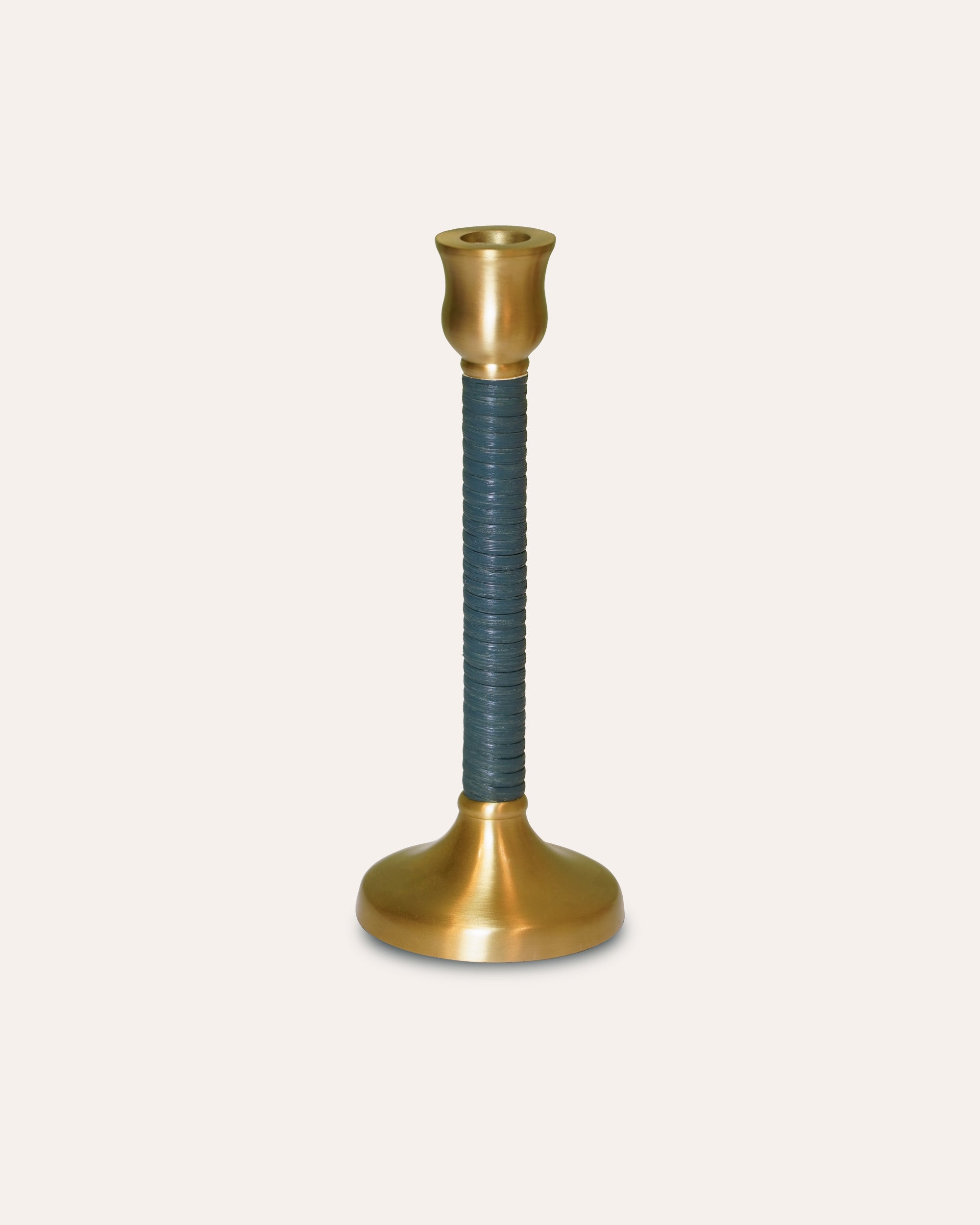 Decorative candle holder with brass base and top, and black ribbed middle section on a beige background