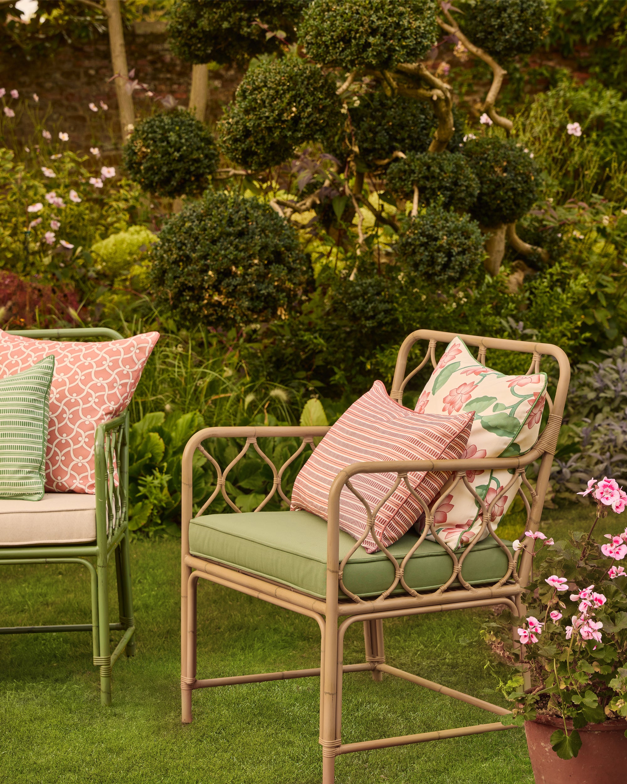 Garden Curato armchair with decorative cushions surrounded by greenery and flowers