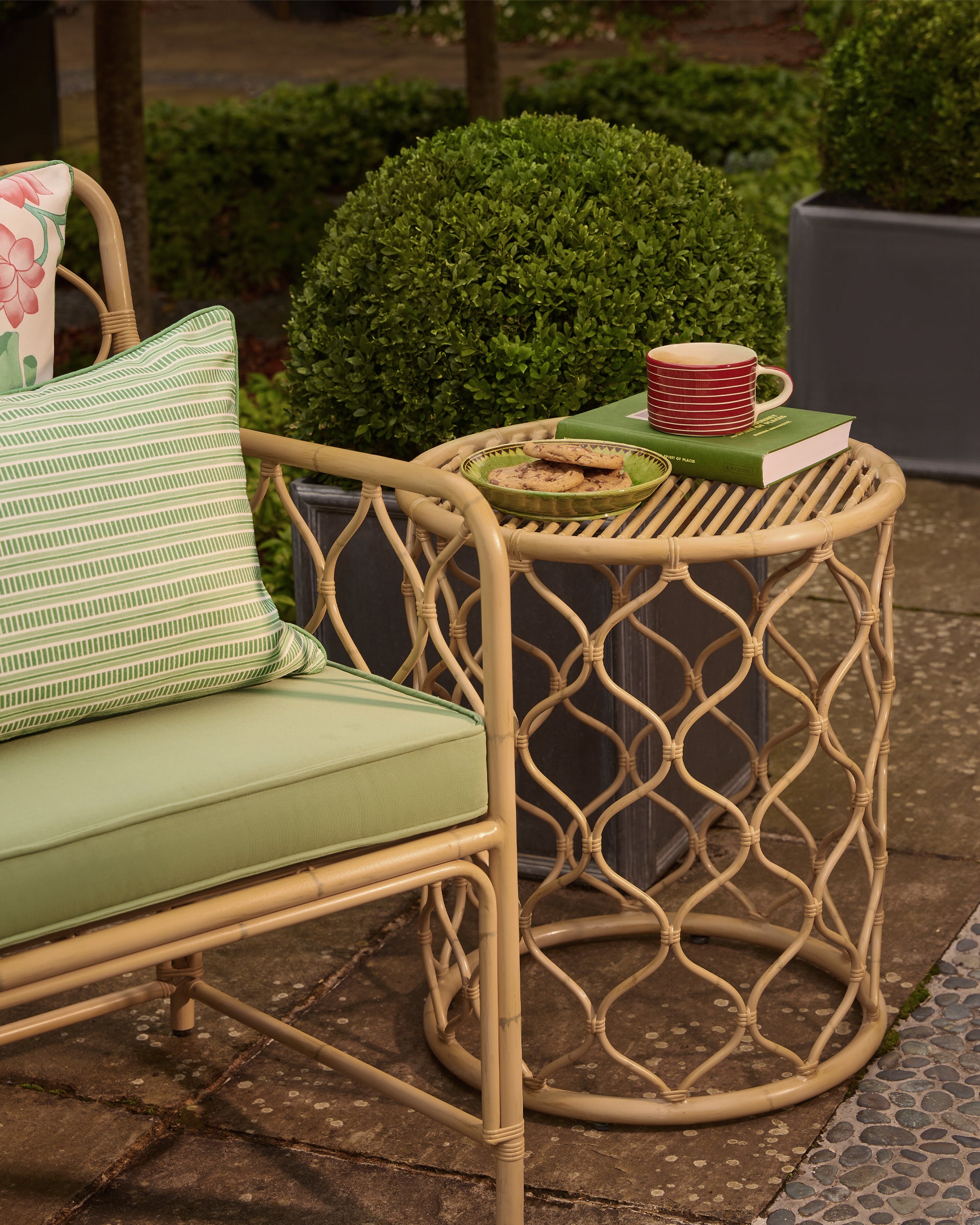 Outdoor patio setting with a natural Curato aluminium chair and side table on a stone patio.