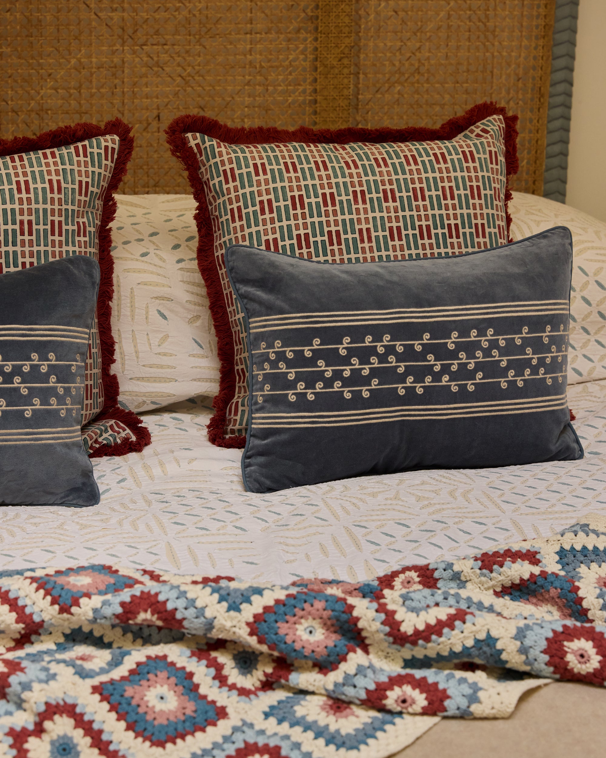 Ladrillo Tile Print Fringed Cushion - Red & Blue, on a bed