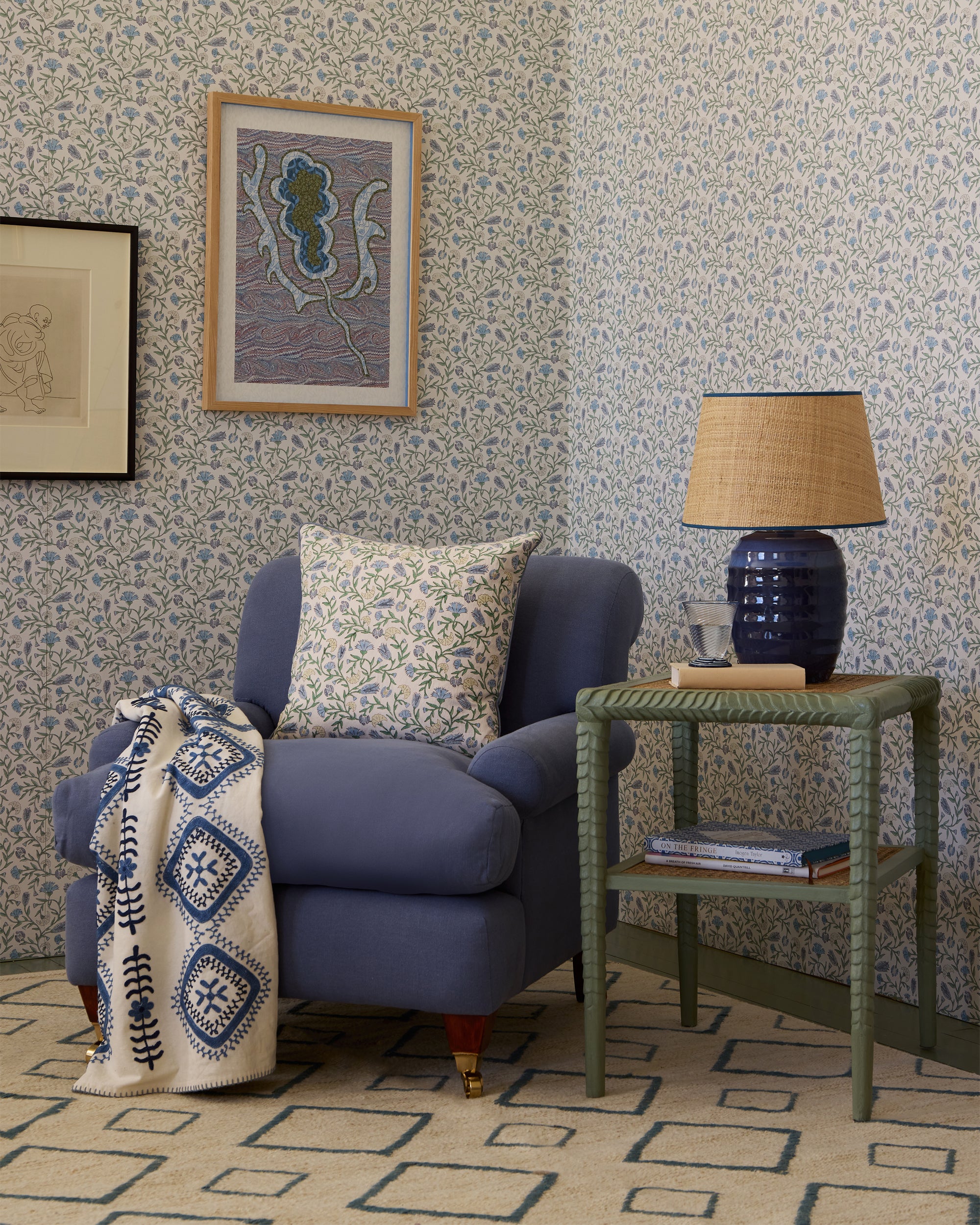 Living room with blue armchair, side table, and decorative elements against a patterned wall.
