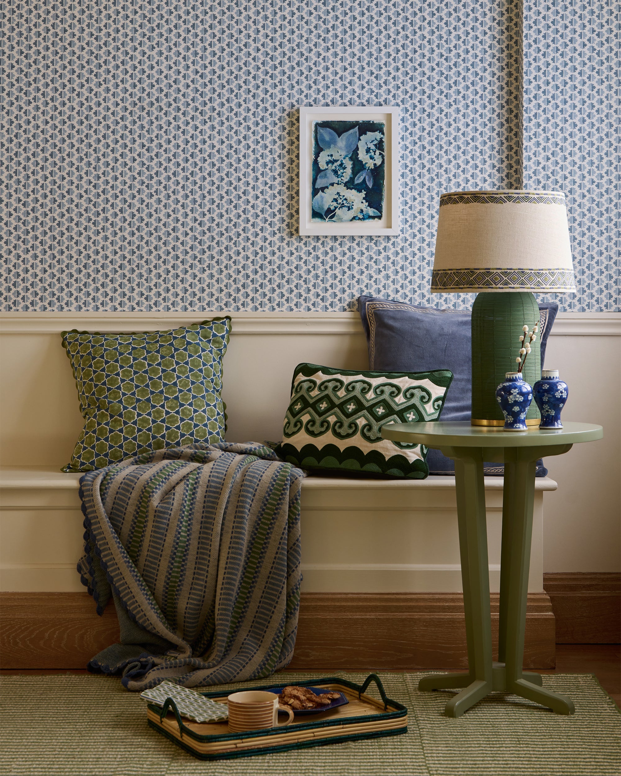 Living room with a bench, pillows, and a lamp against a patterned wall.