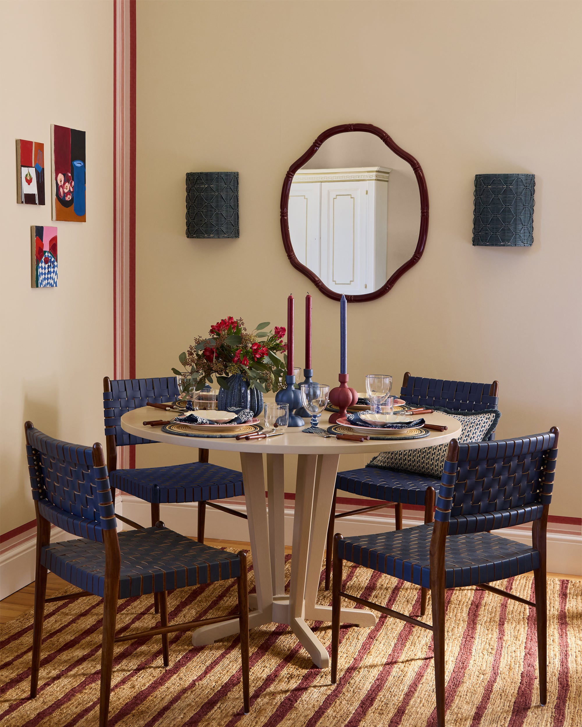 Red and blue dining setting, featuring a striped red rug, blue leather woven dining chairs and taupe pedestal table