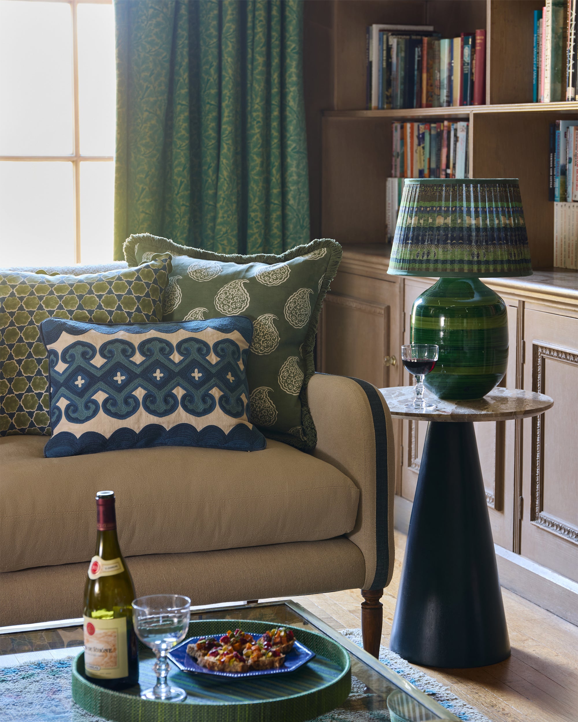 Living room with beige sofa, decorative cushions, and a small table with wine and snacks.