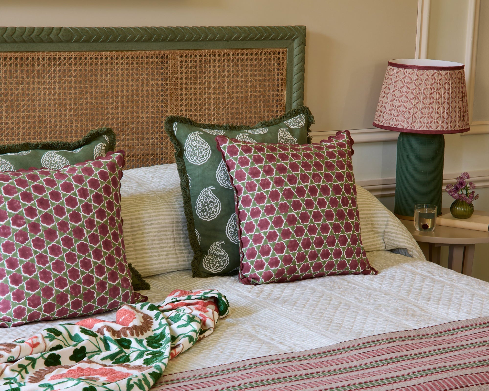 Bedroom with a bed featuring patterned bedding and pillows, a lamp, and a painting on the wall.