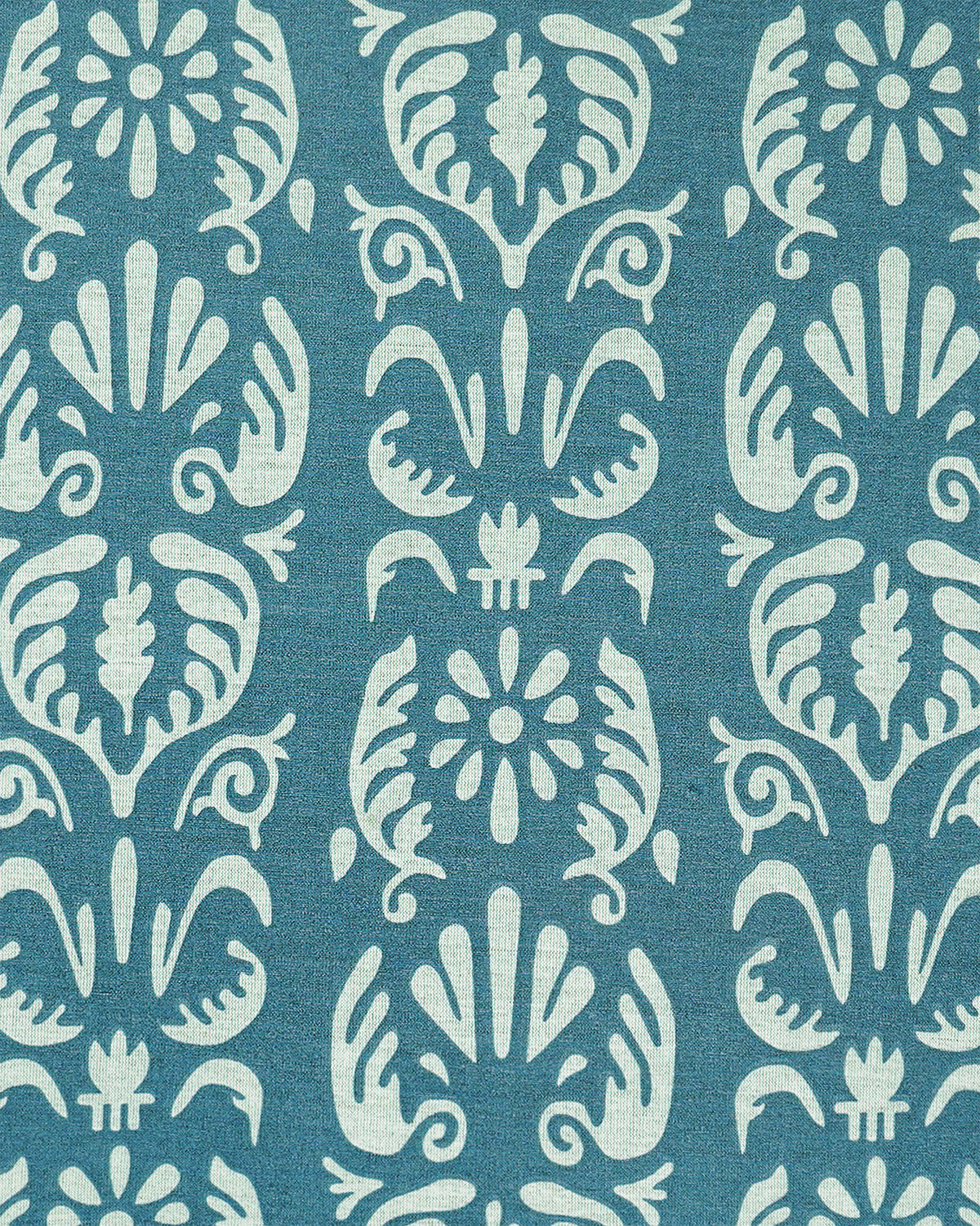 A close-up of a cushion featuring a repeating vertical damask-style design in teal blue and off-white.