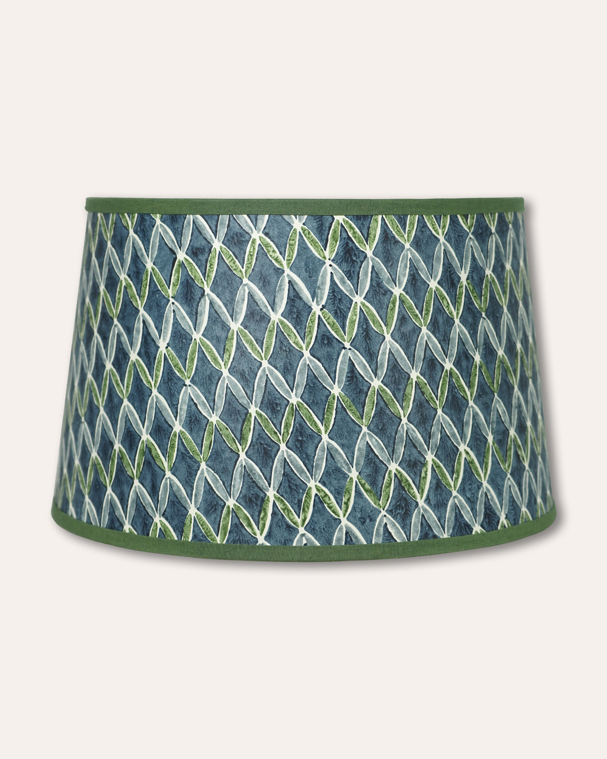 A tapered drum lampshade featuring a blue and green geometric pattern with a solid green top and bottom trim, shown against a light beige background.