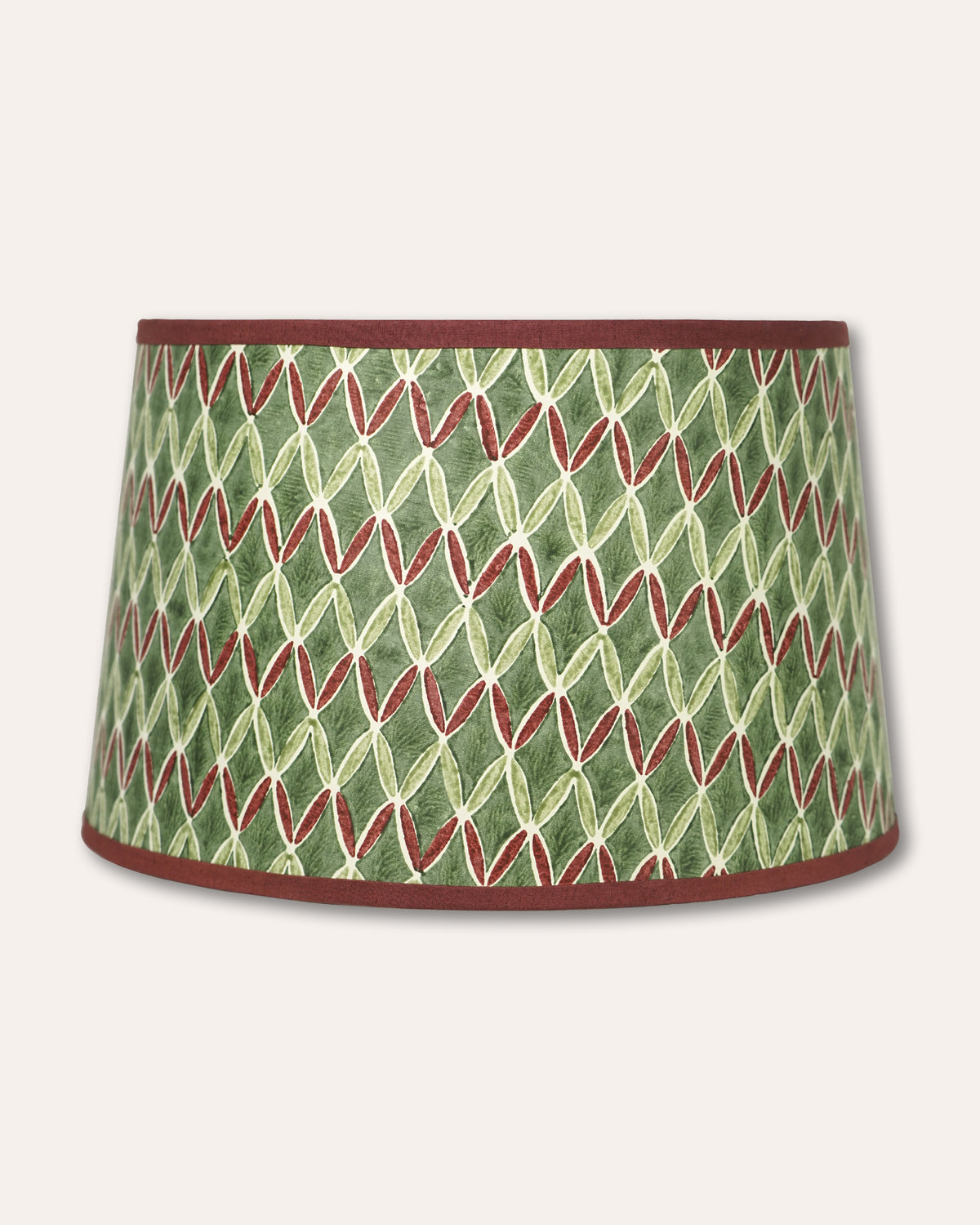 A tapered fabric lampshade featuring a green and cream geometric leaf pattern with red-brown trim at the top and bottom edges, shown against a light beige background.