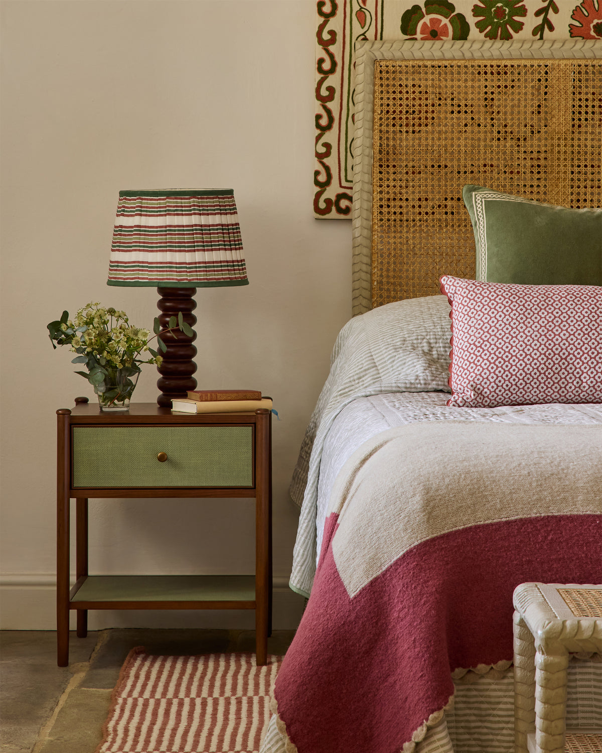 Bedroom with a nightstand, lamp, and decorative pillows on a bed.