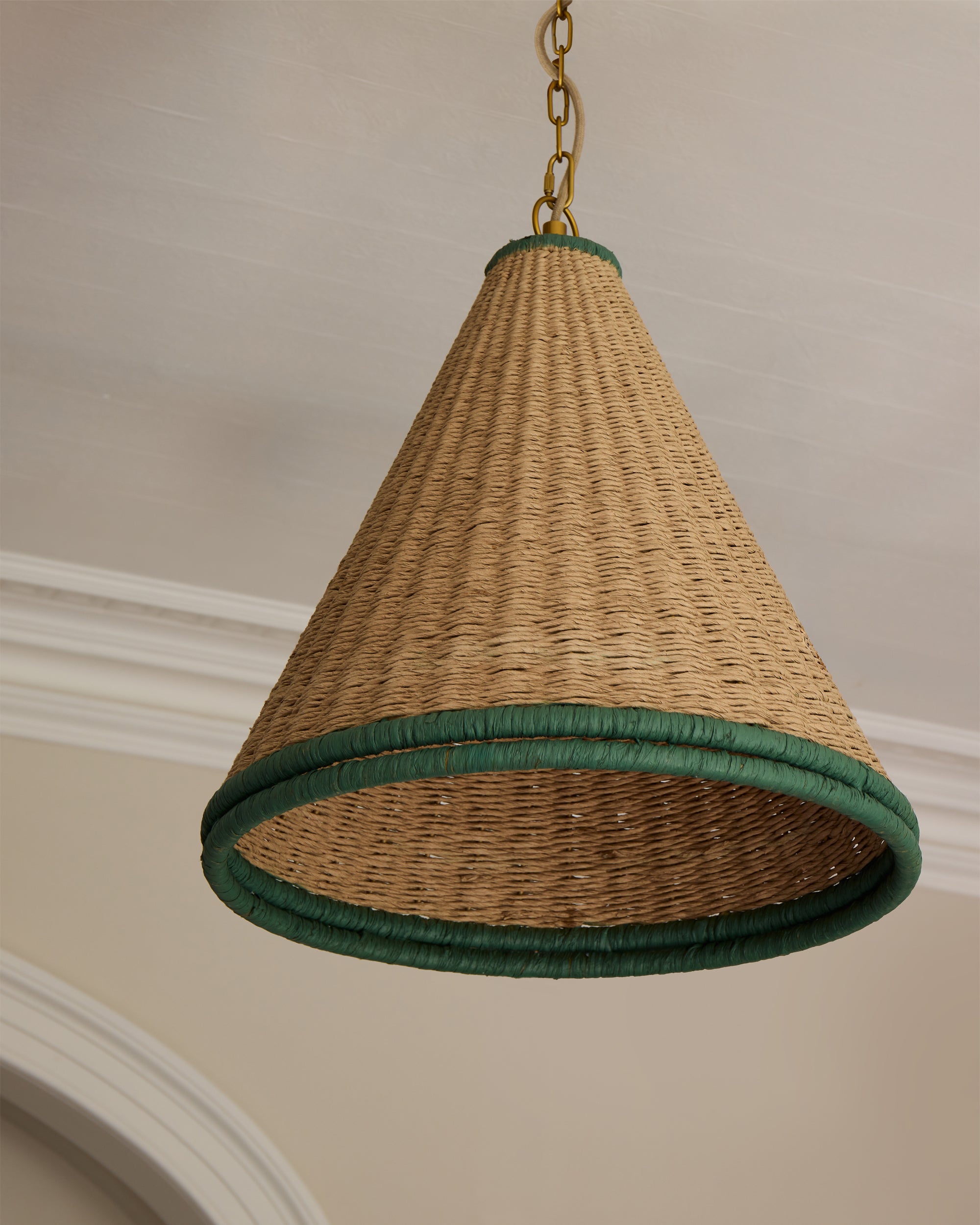 Woven pendant light with green trim hanging from a ceiling.