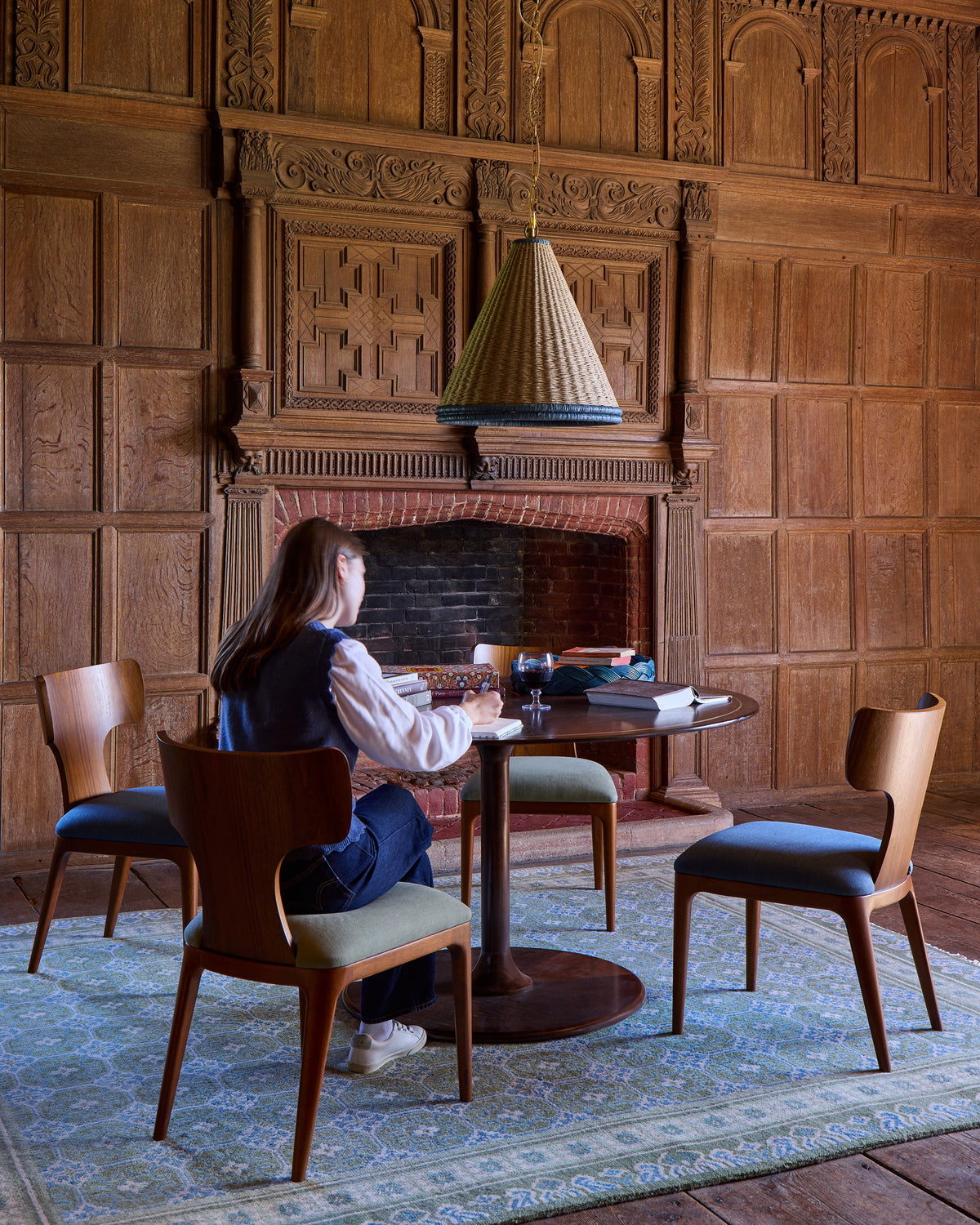 Woman sitting at a table in a room with wooden walls and chairs.