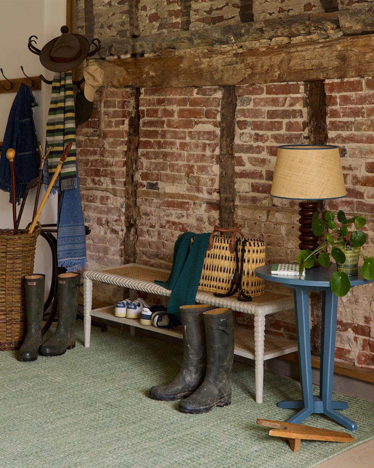 Room with brick wall, wooden bench, boots, and a lamp.