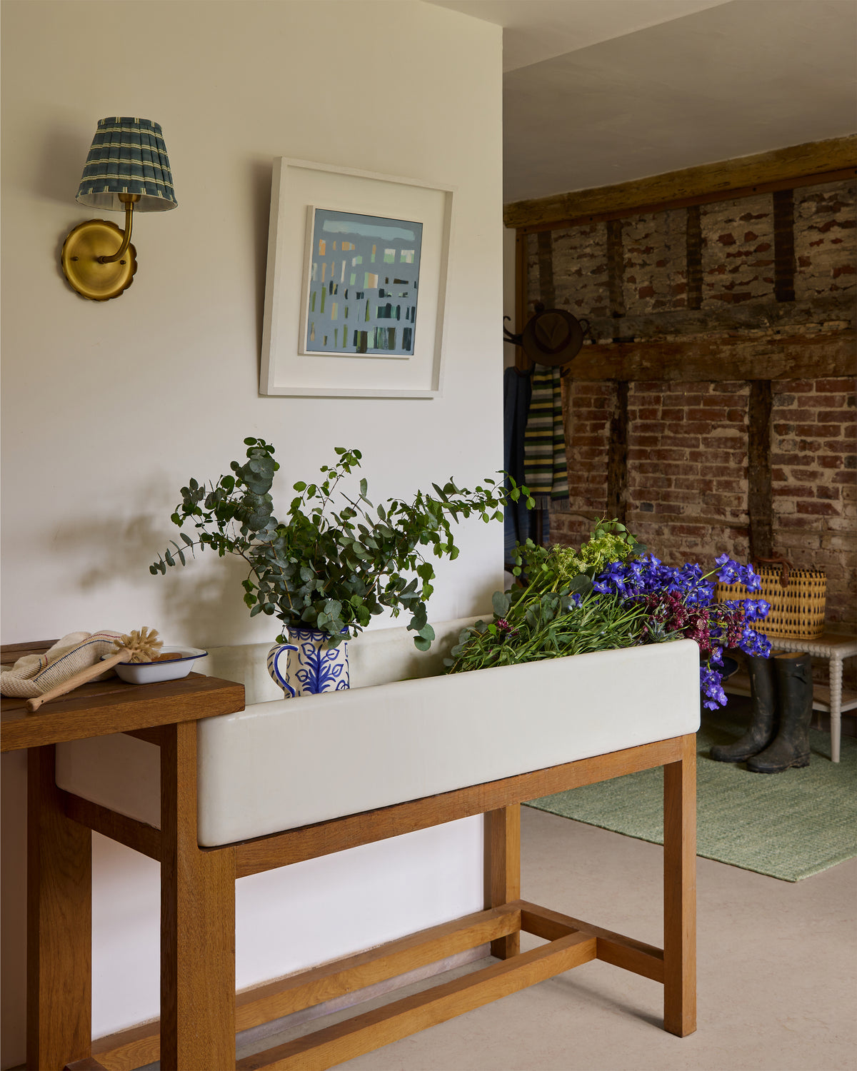 Room interior with wooden bench, white cushion, potted plants, and framed artwork on a wall.