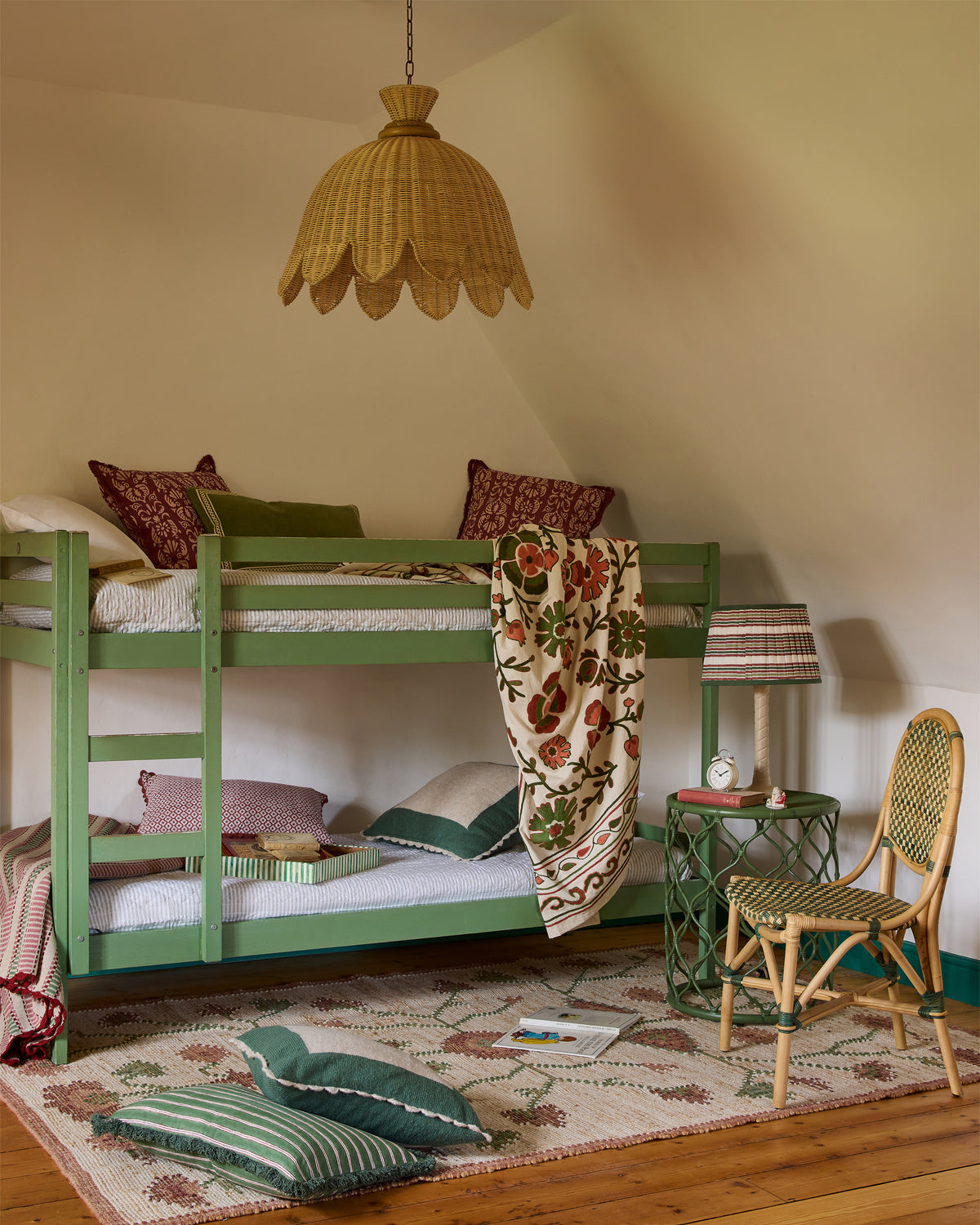Children's bedroom with green bunk bed, floral rug, and wooden chair.