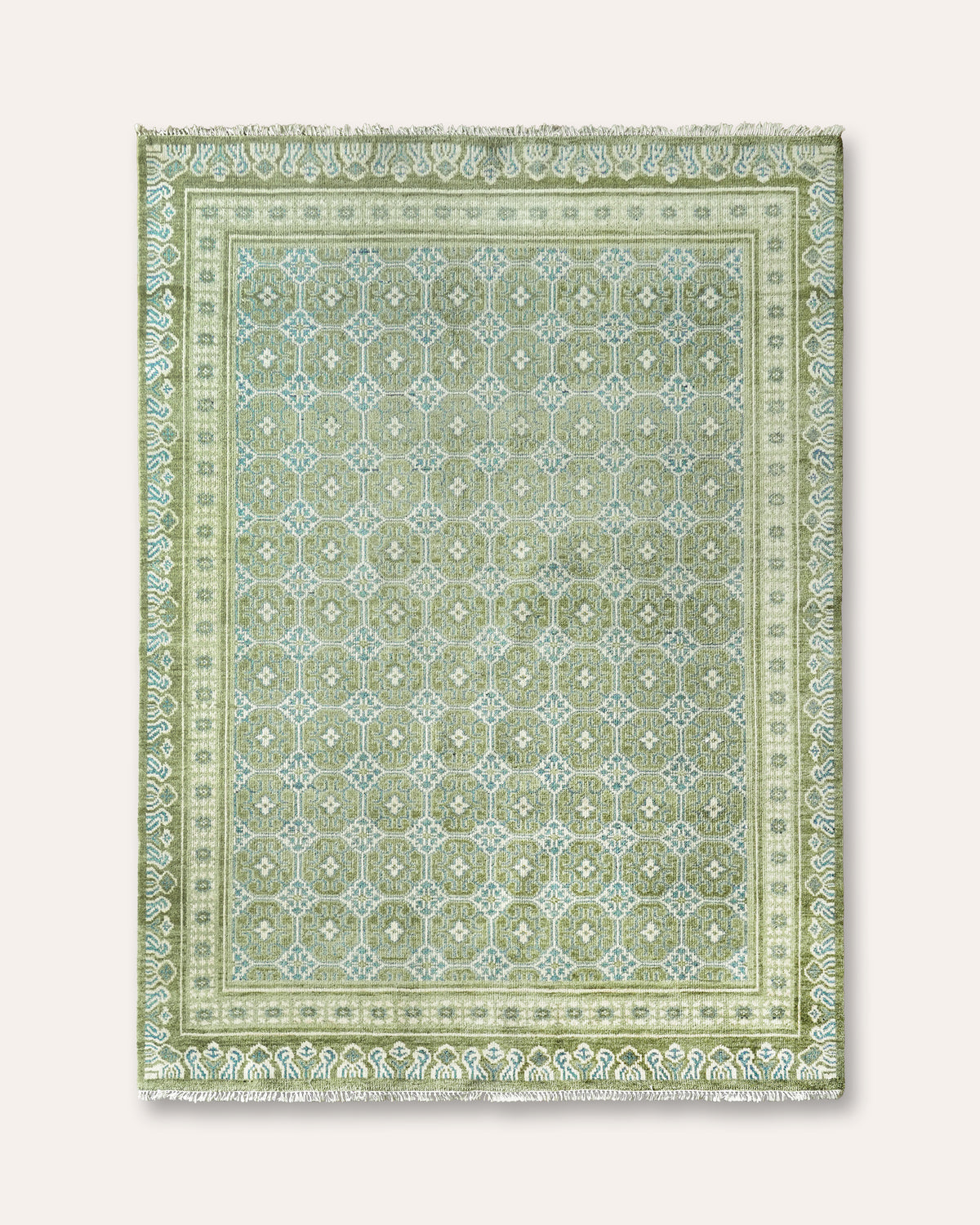 A rectangular area rug with a traditional geometric pattern in shades of sage green, light green, and cream, featuring a fringed edge.
