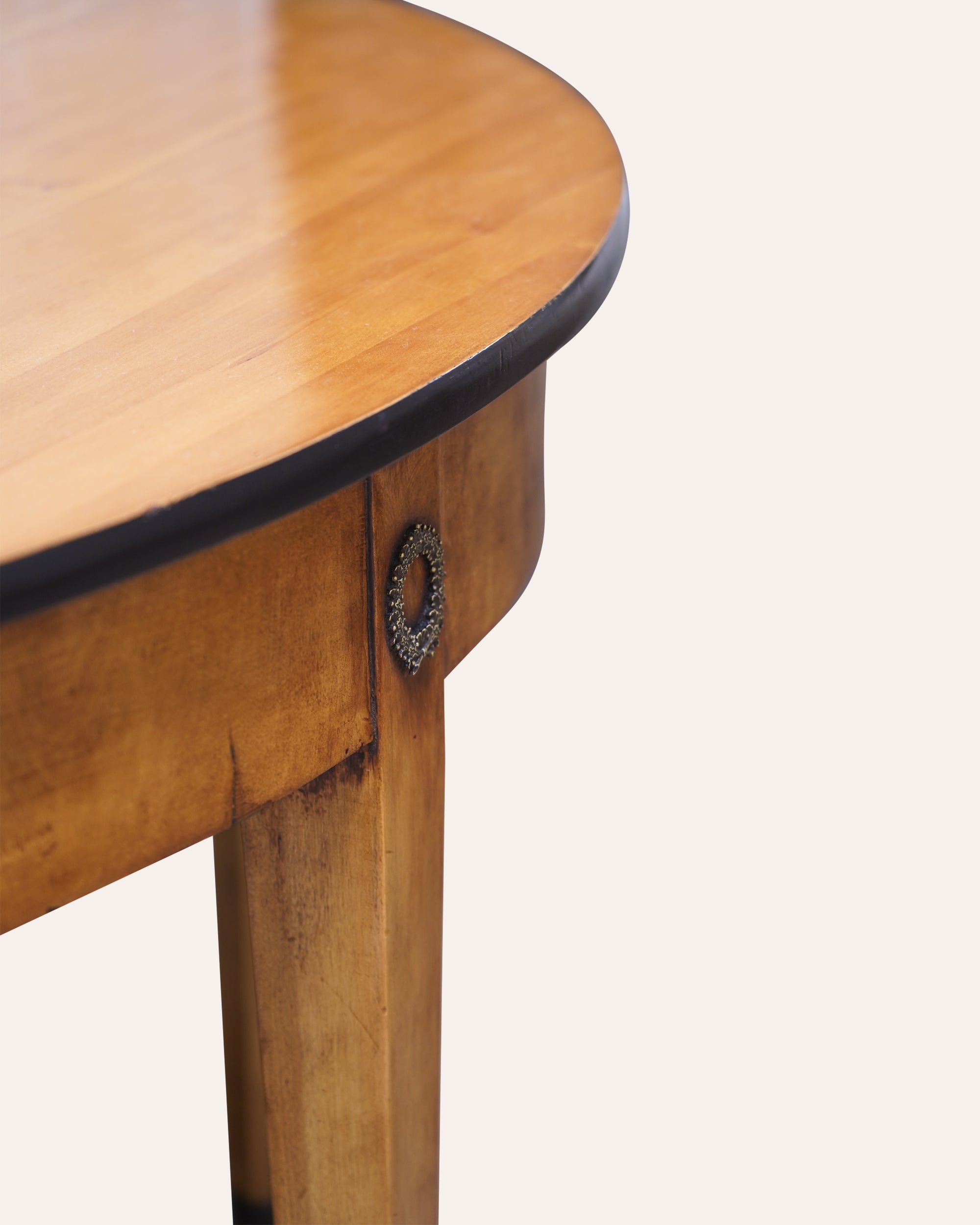Close-up of a wooden side table with a round top and decorative knob on a white background