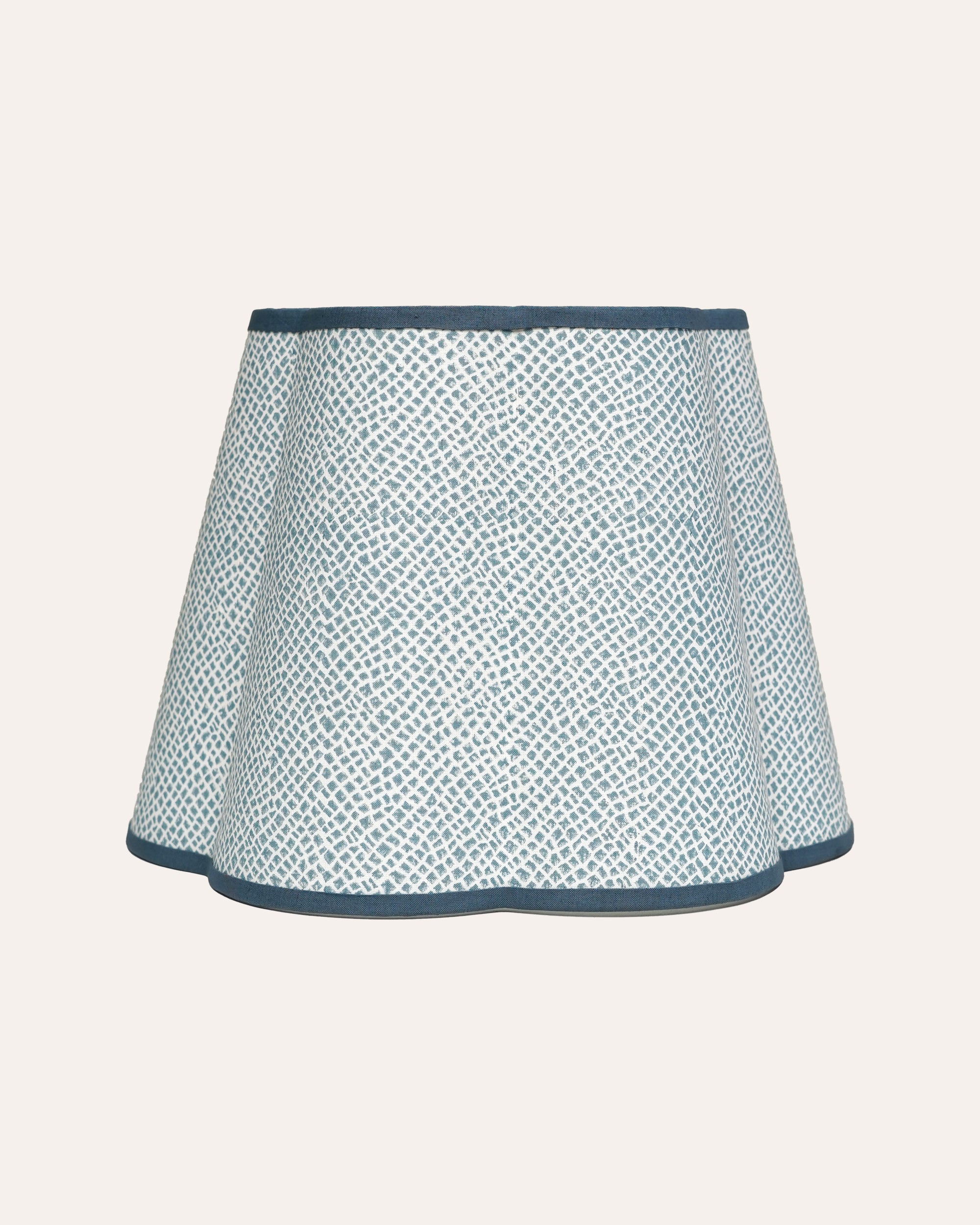 A blue scalloped lampshade with a geometric tile pattern.