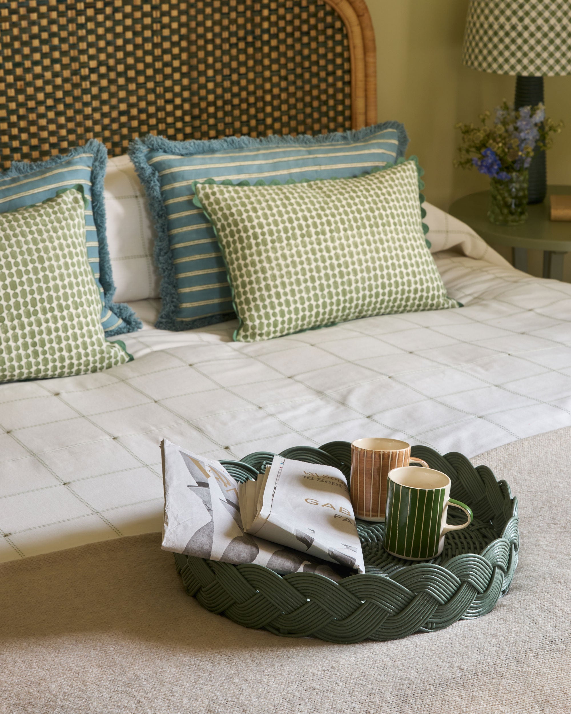 Bedroom scene with cushions, a tray, and decorative items on a bed.