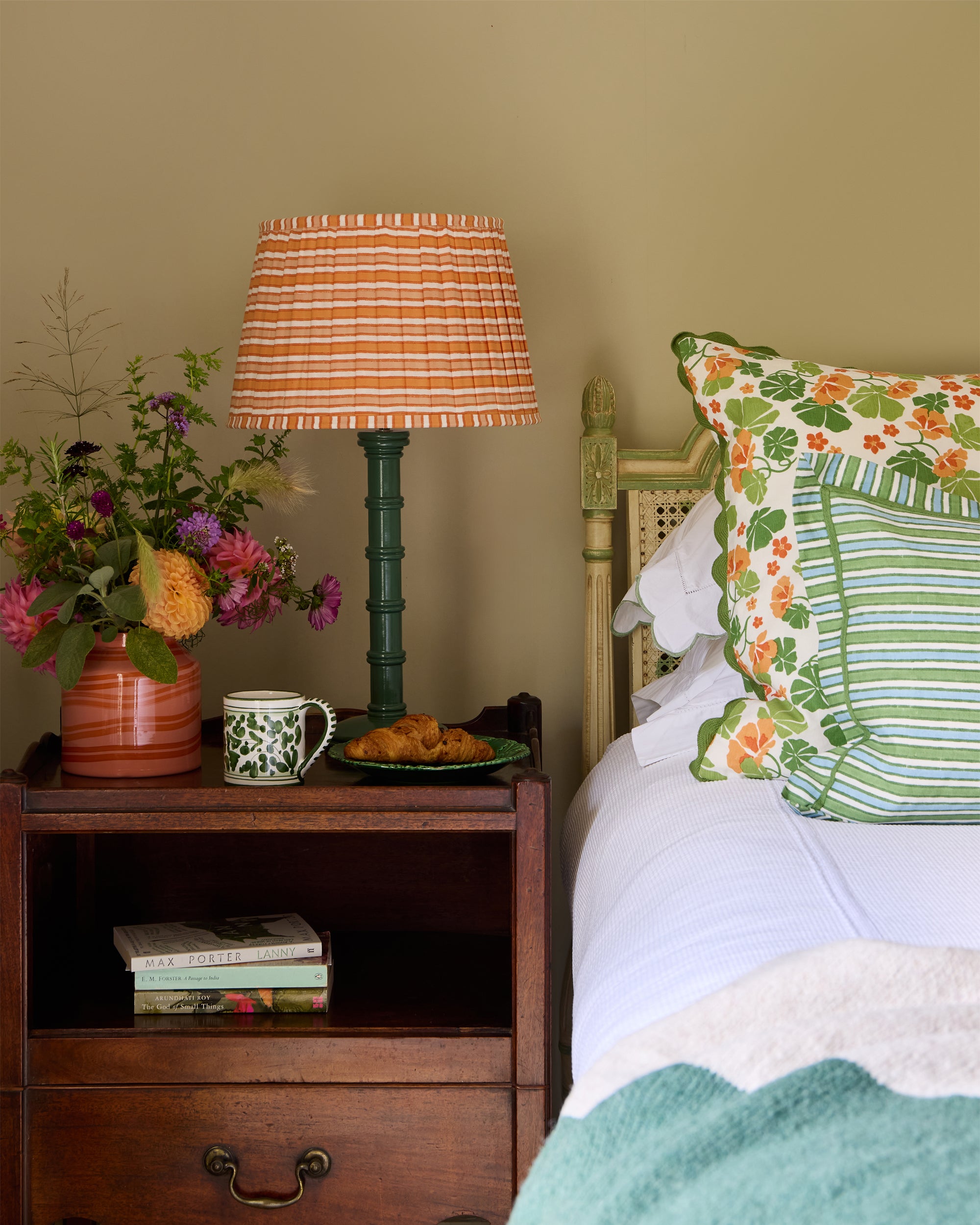 Bedside table featuring the green Column lamp, sunset striped lampshade next to the orange and pink Maypole vase
