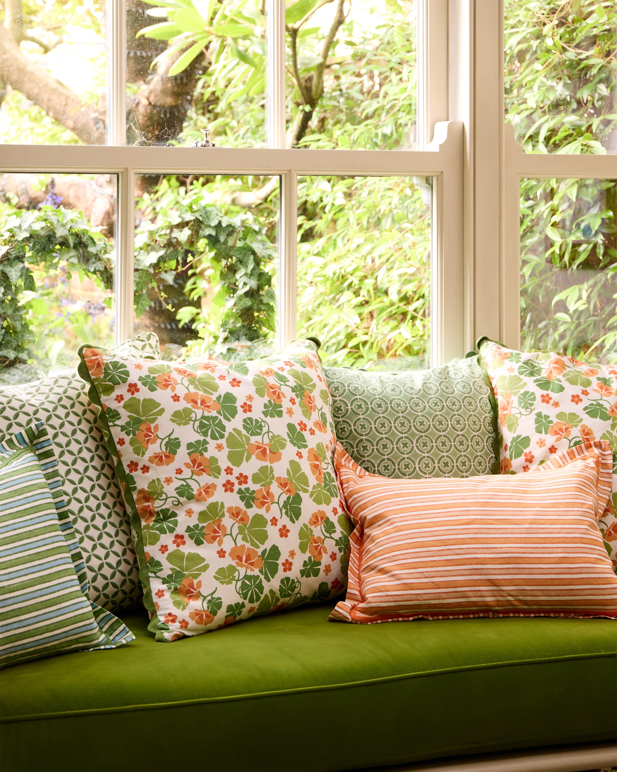 Summer window seat covered in floral and striped cushions from the Nasturtium collection