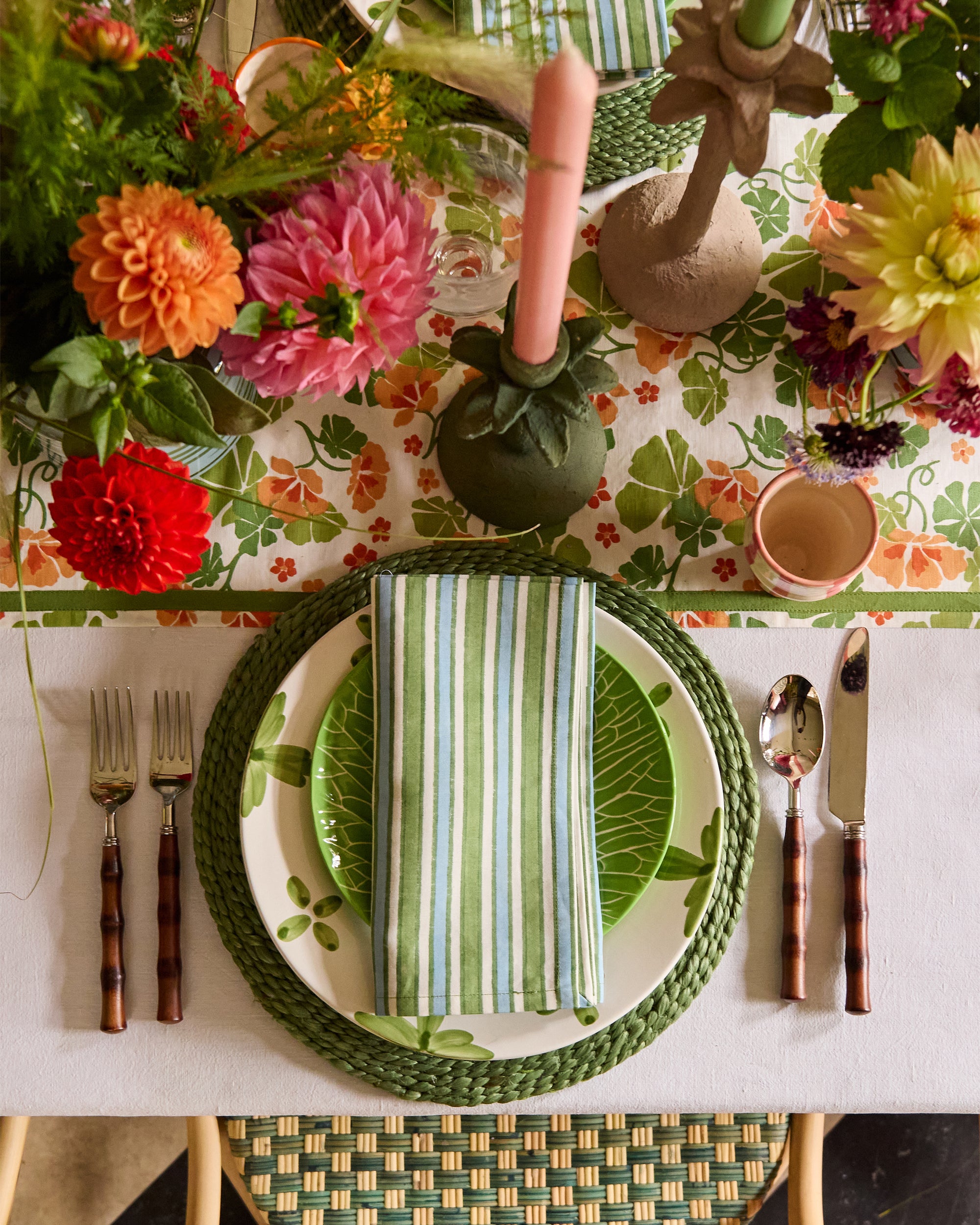 Beautiful tablescape close up, showcasing the striped blue and green napkin, the nasturtium table runner and palm leaf candlesticks