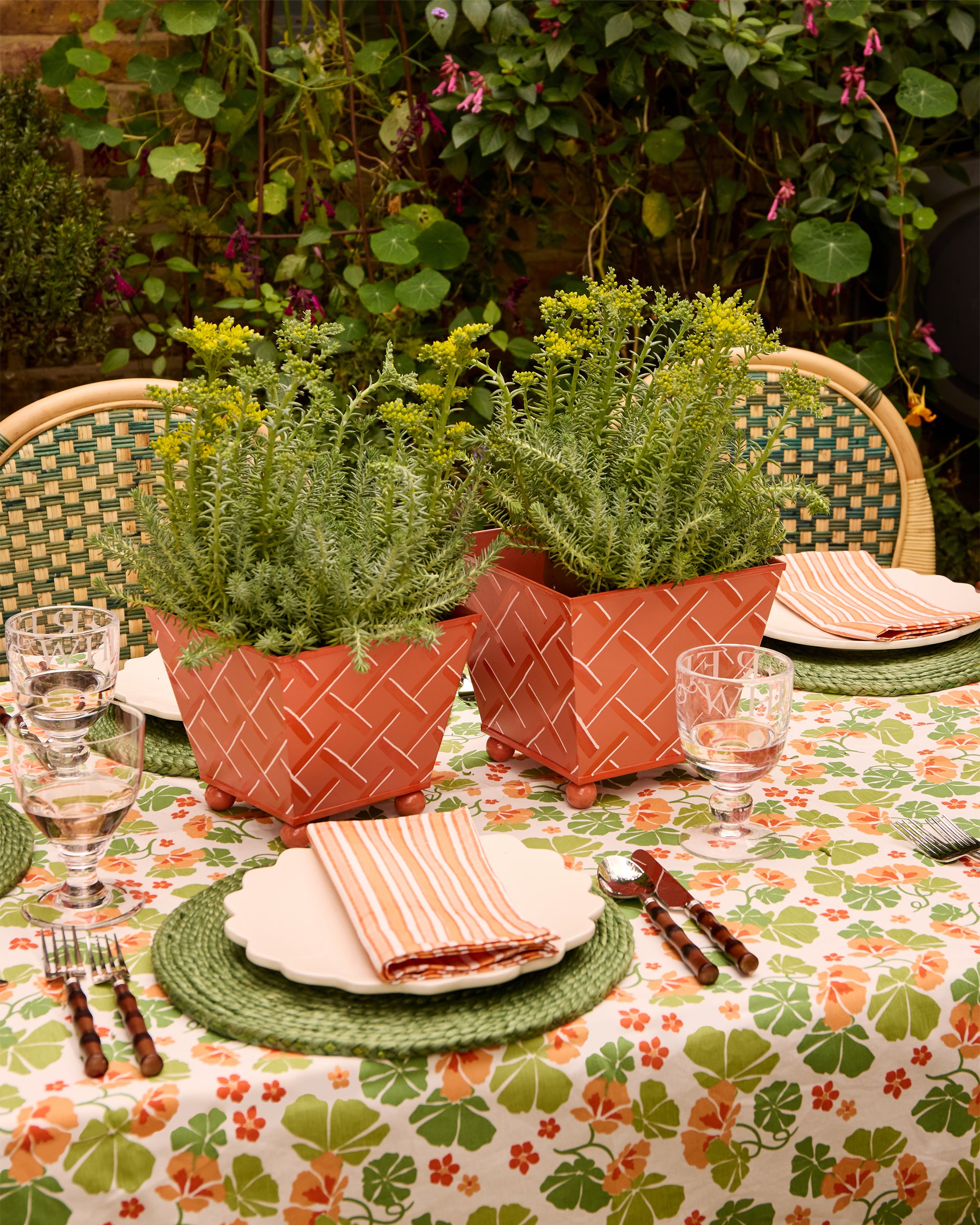 Beautiful orange and green outdoor dining tablescape, styled with the Nasturtium tablecloth, sunset striped napkins and tole planter centre pieces