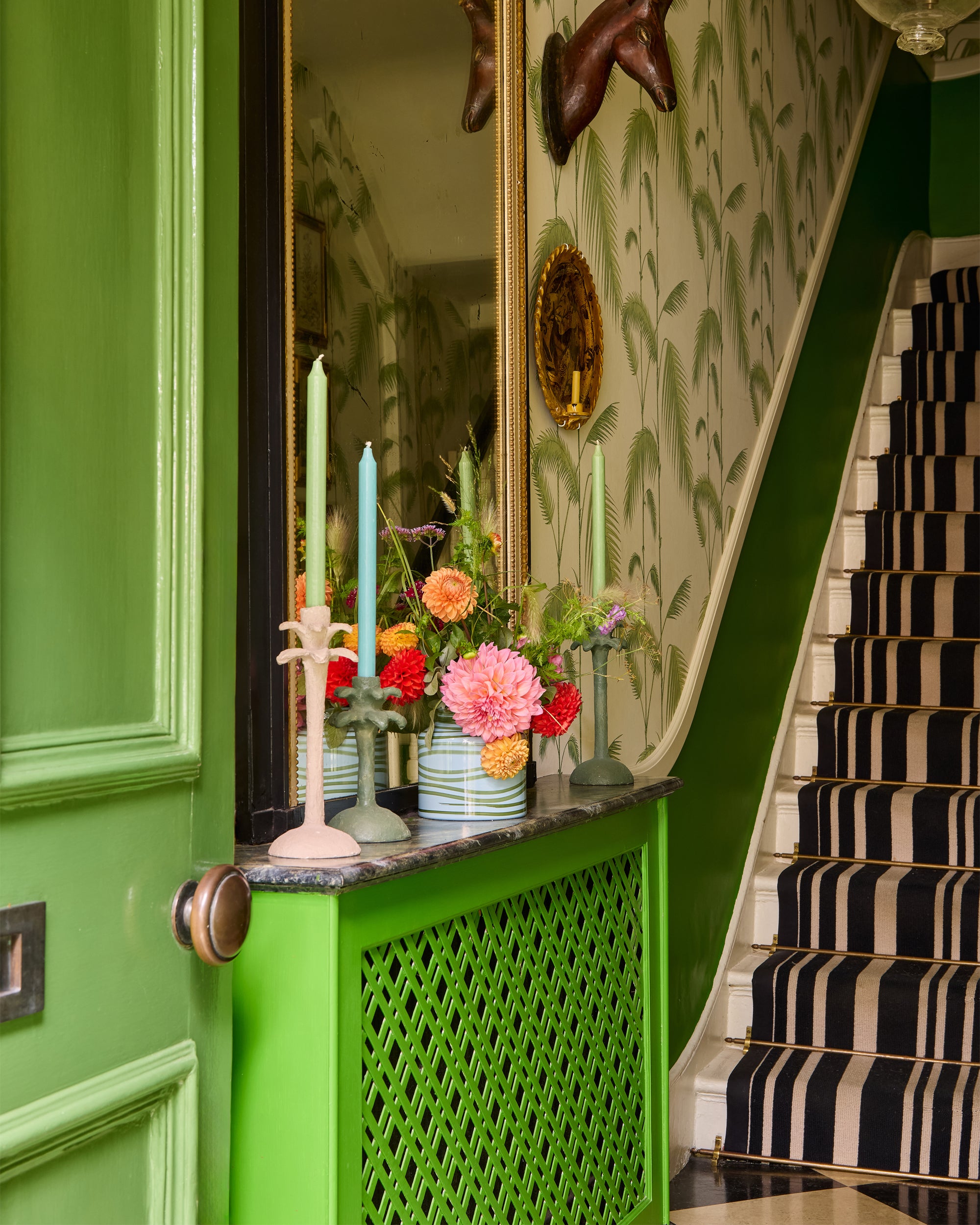Close up lifestyle image of Butter Wakefield's hallway, featuring the blue and green Maypole vase and palm tree candlesticks in green and taupe