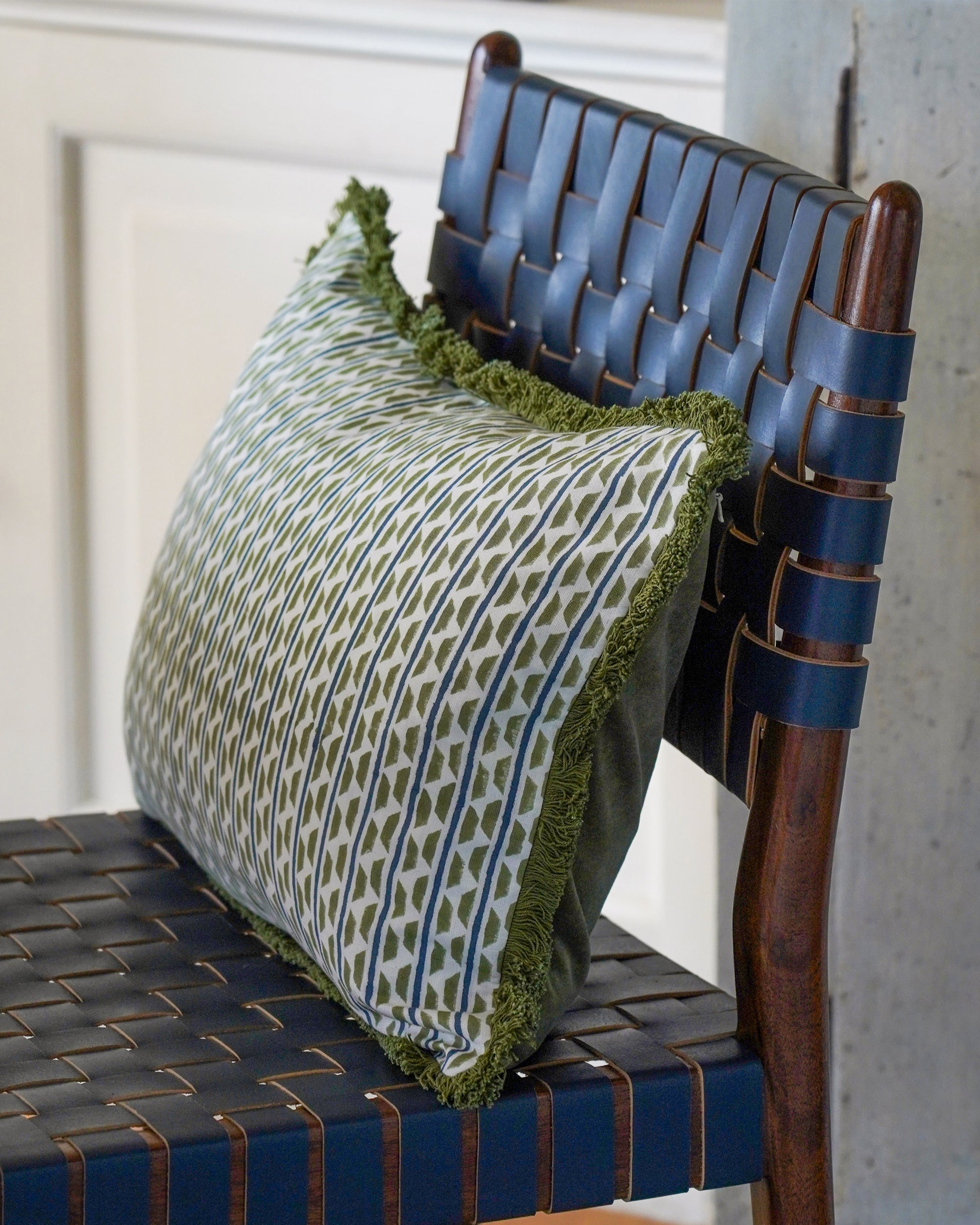 Green patterned cushion on a woven blue leather chair