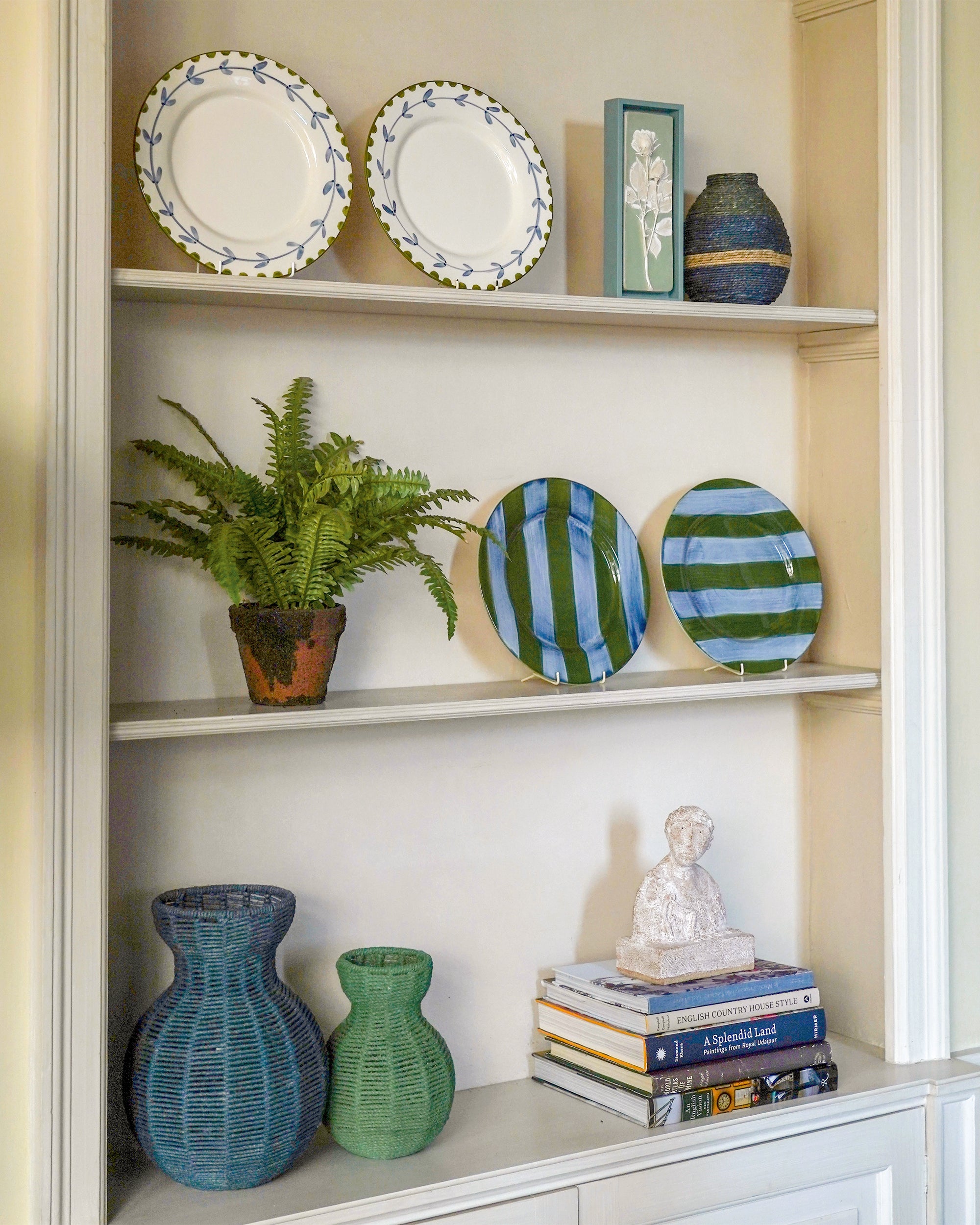 Decorative bookshelf with plates, vases, and a plant