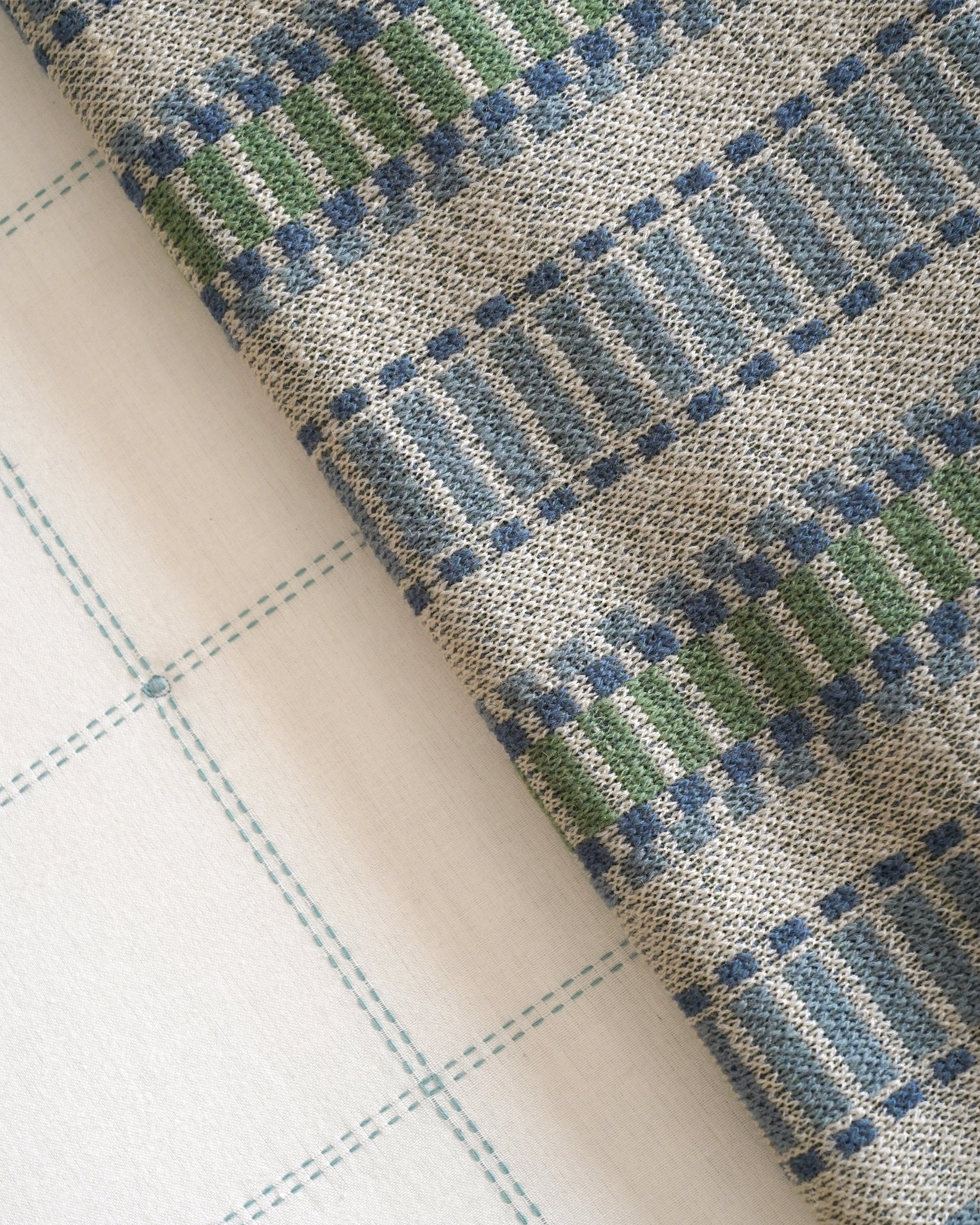 Close-up of fabric with a checkered pattern in blue and green on a beige background