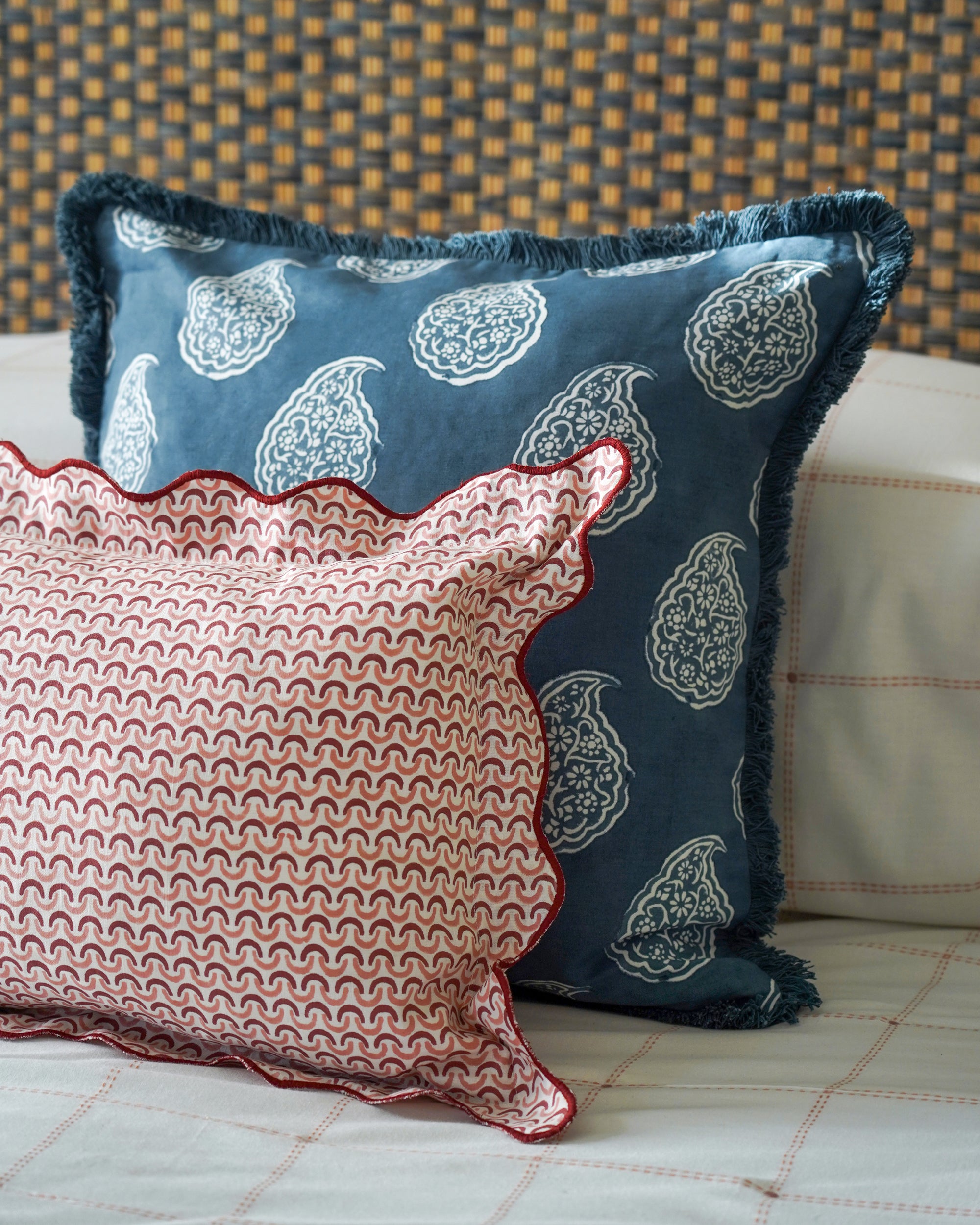 Two patterned cushions on a sofa with a textured headboard background