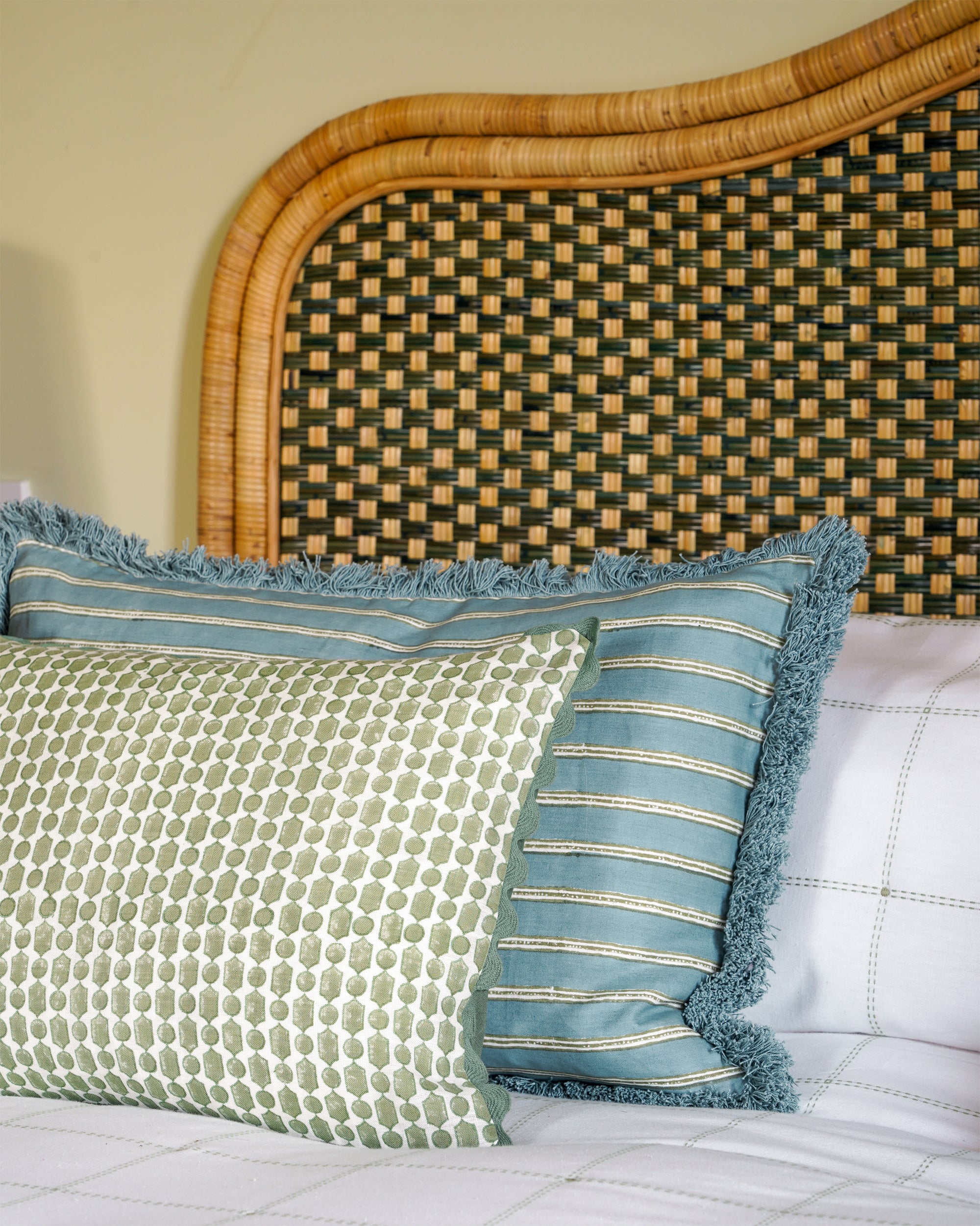 Decorative cushions on a bed with a wicker headboard
