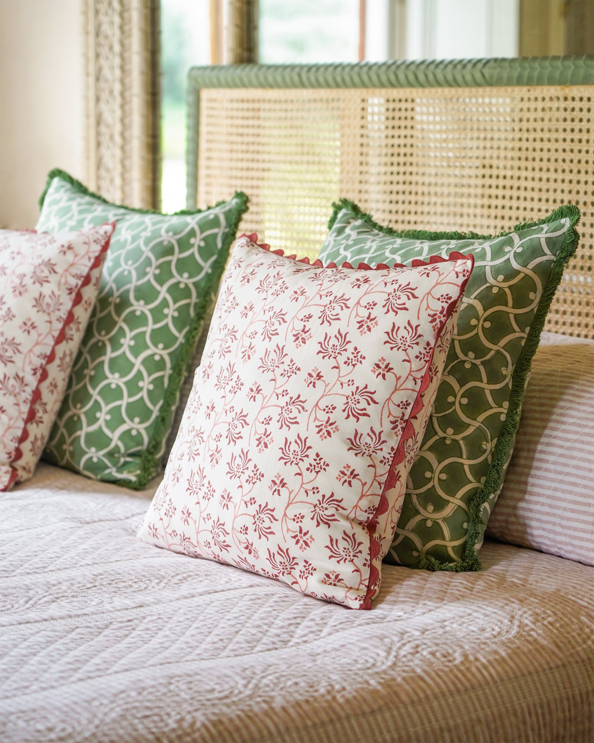 Decorative pillows with green and red patterns on a bed