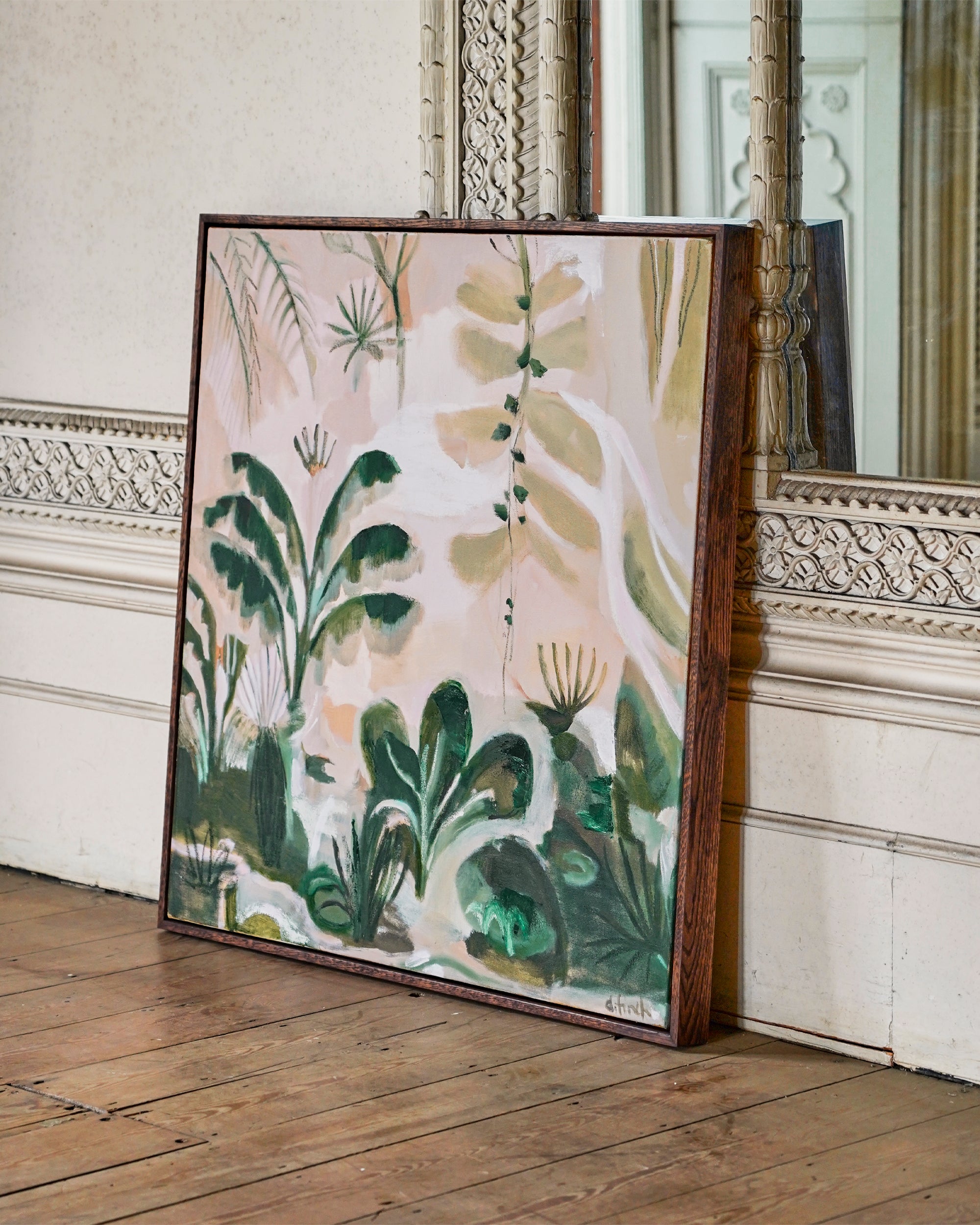 Framed botanical artwork on a wooden floor with decorative wall molding.