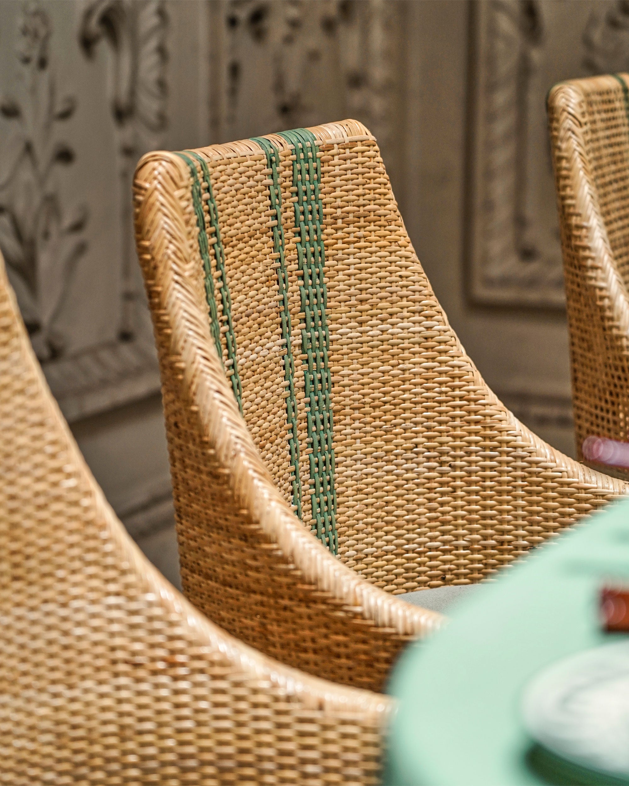 Close-up of woven chairs with a decorative wall in the background