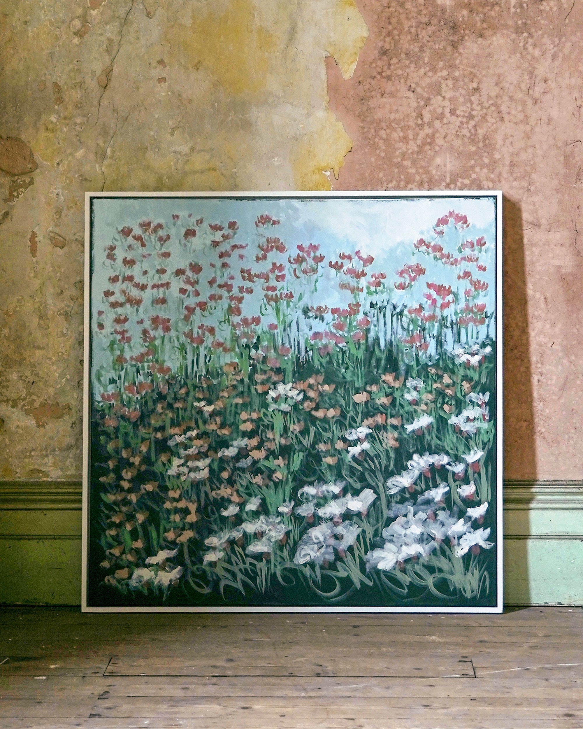 Framed artwork by Claire Oxley of a floral scene on a textured wall.