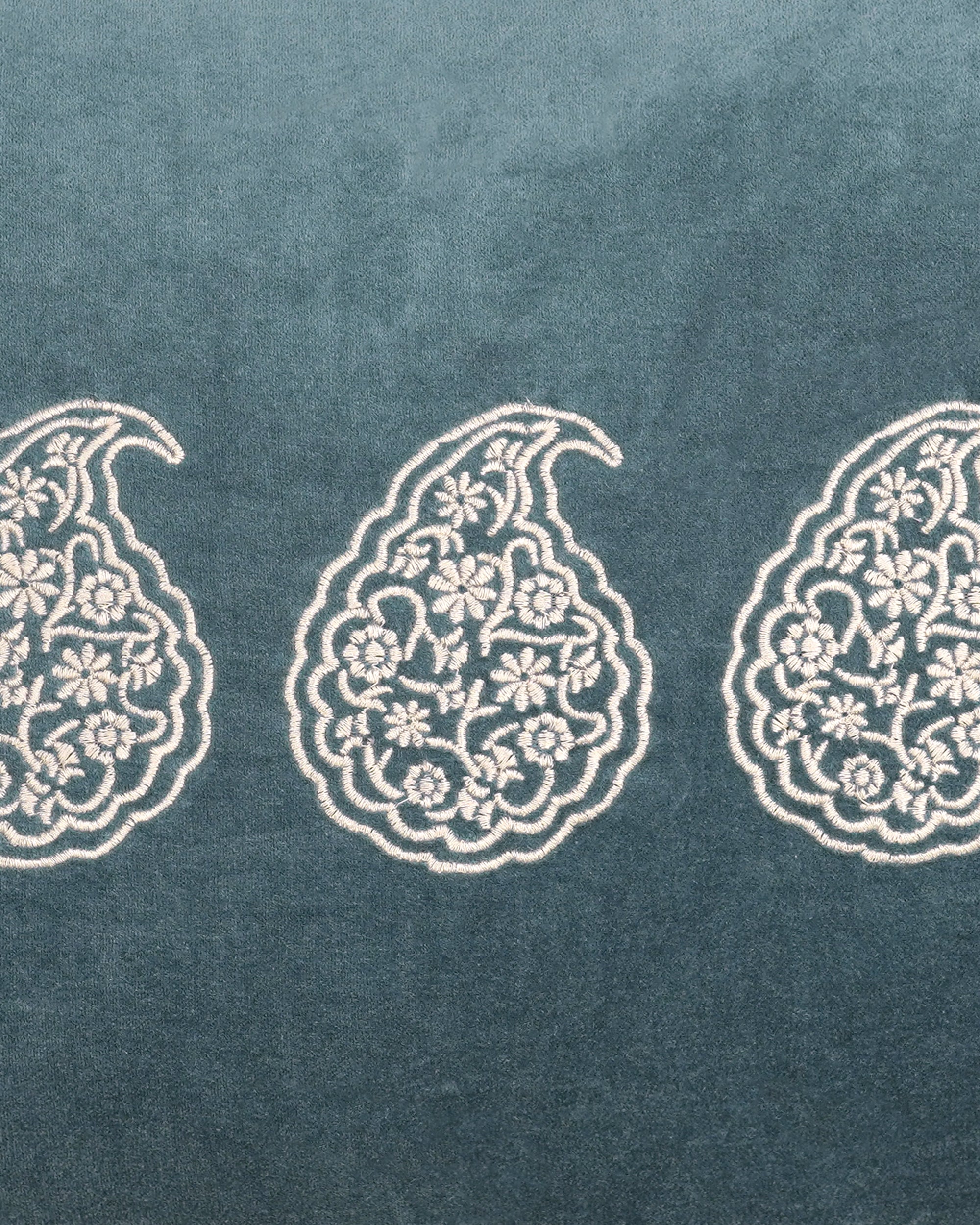 Decorative pattern of paisley shapes on a textured blue fabric background