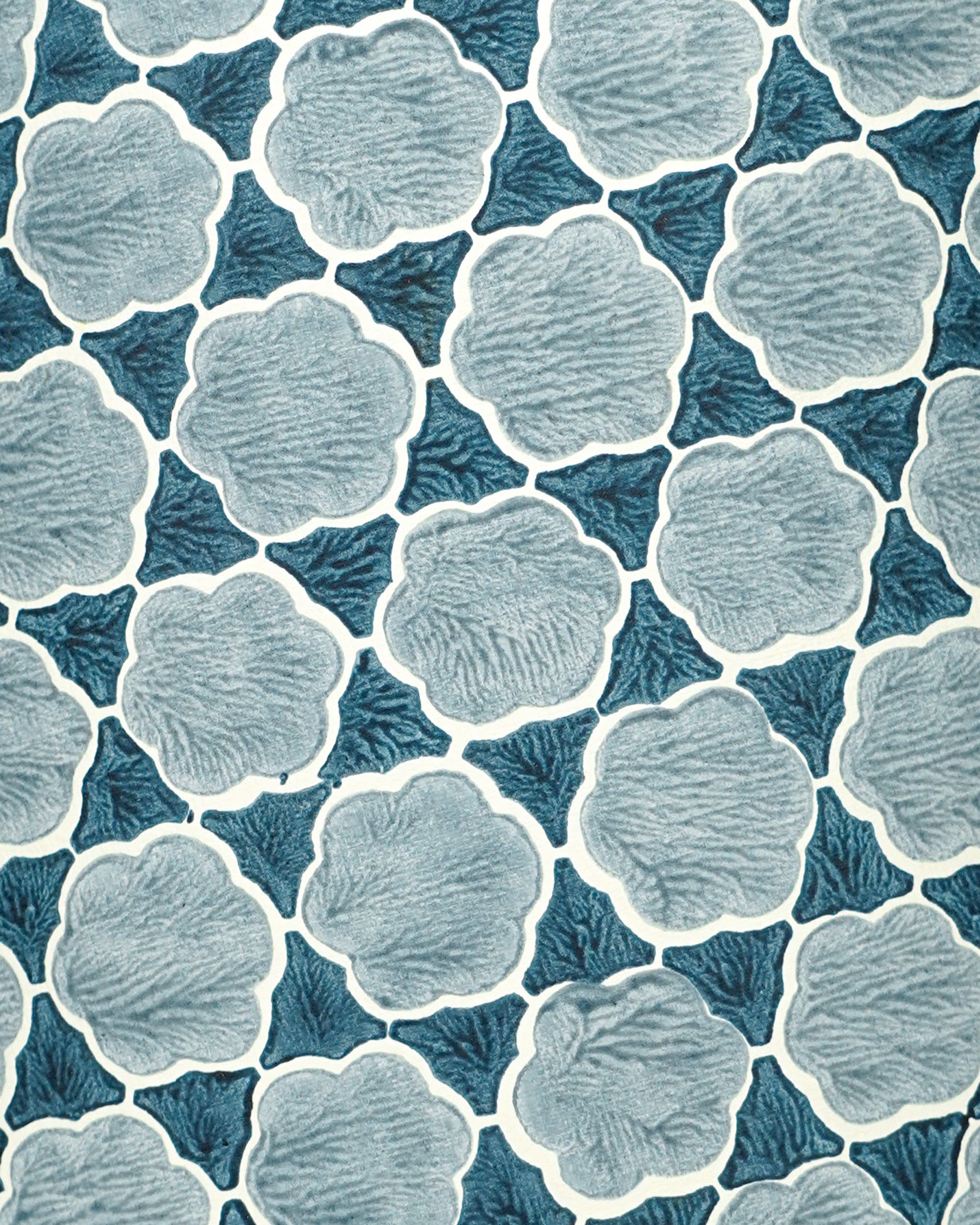 Close up pattern of blue and white floral shapes on a blue background