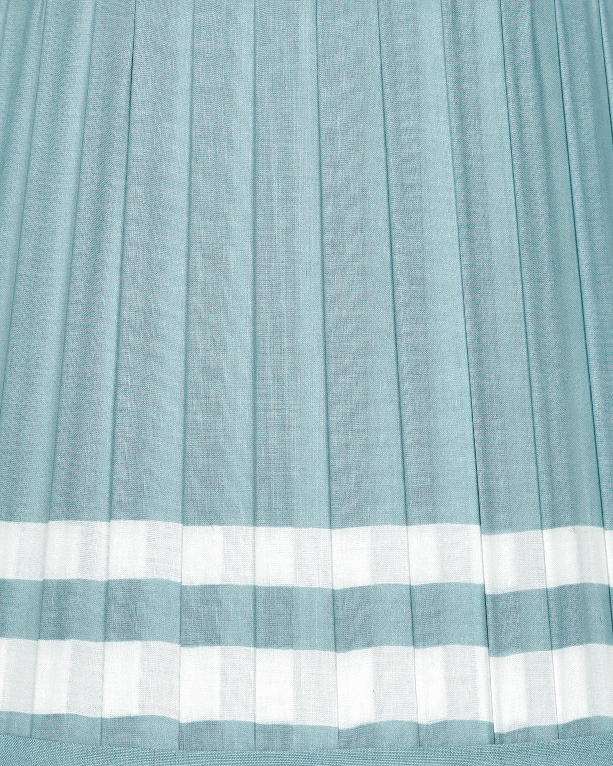 Close-up of a blue and white pleated lampshade with a white border
