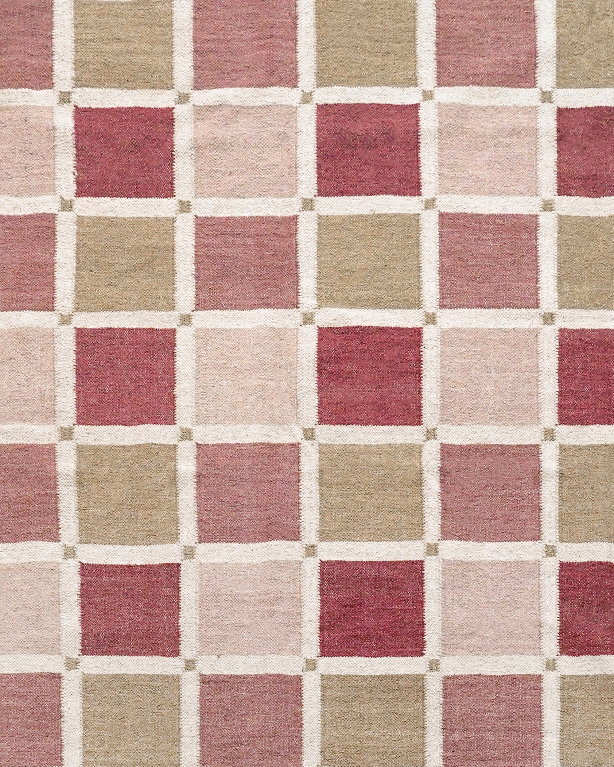 Close up detail of the Shatranj flatweave rug with red, taupe and pink square check patterns