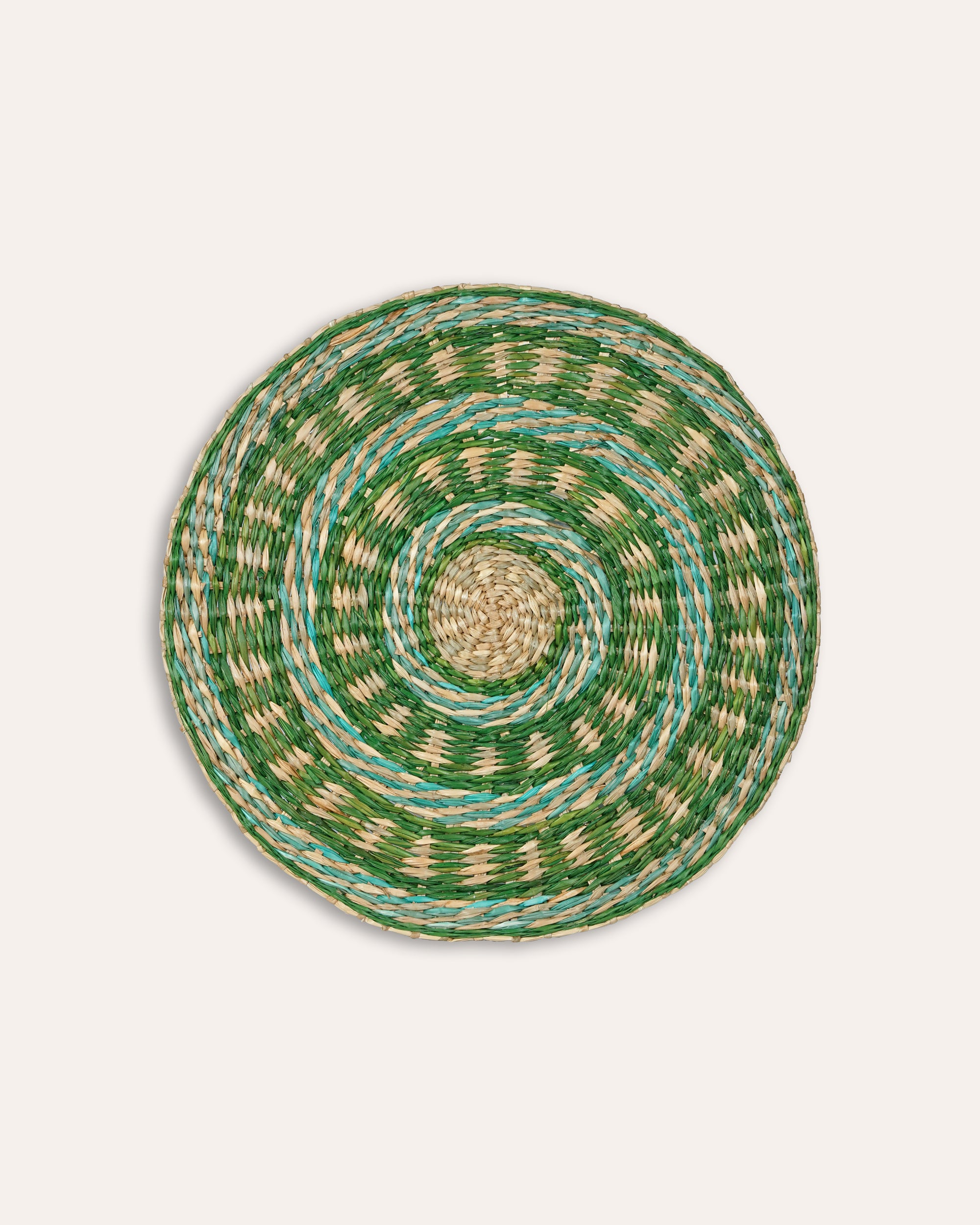Round woven placemat with green and beige pattern on a light grey background