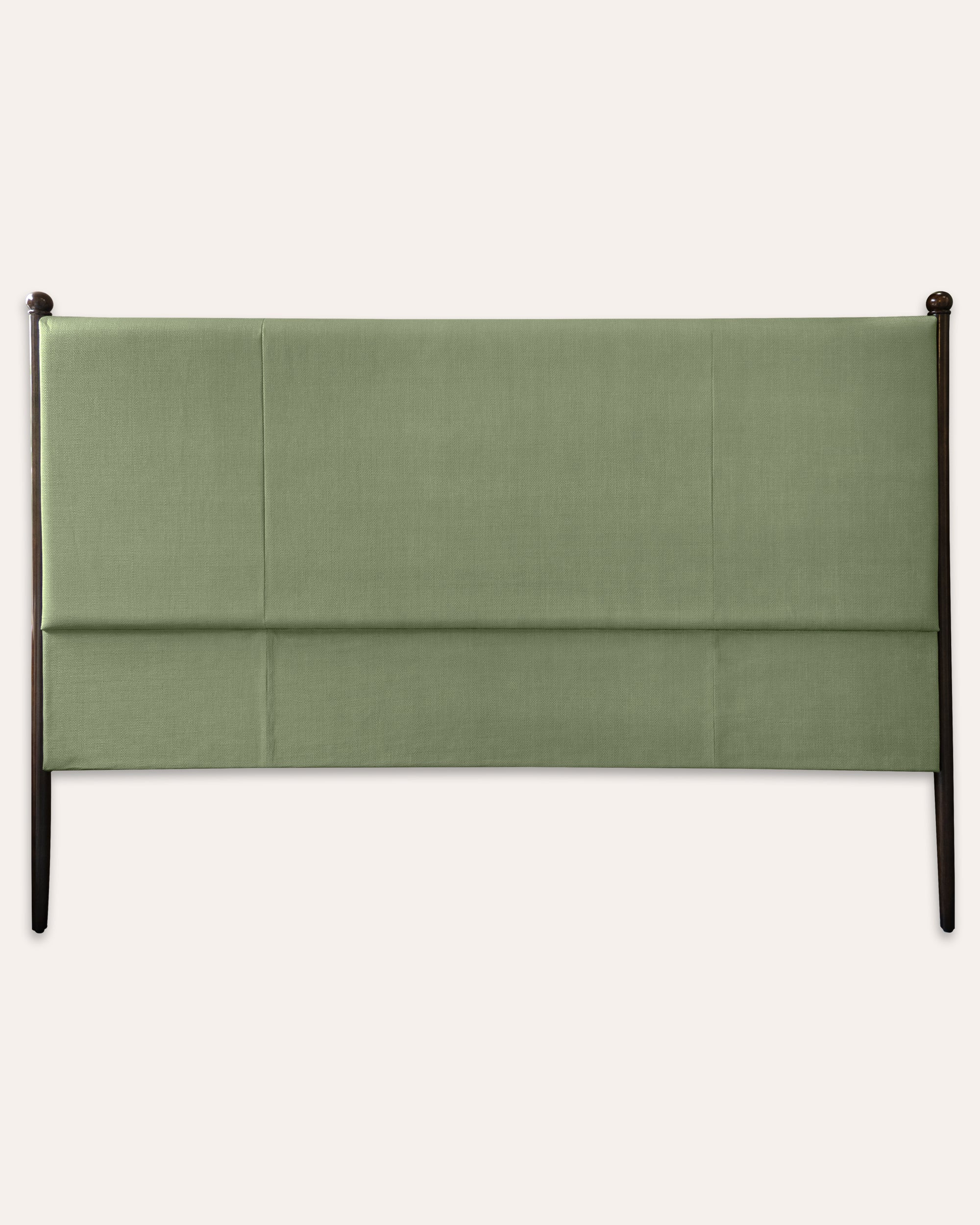 An upholstered headboard with a muted sage green fabric and a dark wood frame, shown against a solid off-white background.